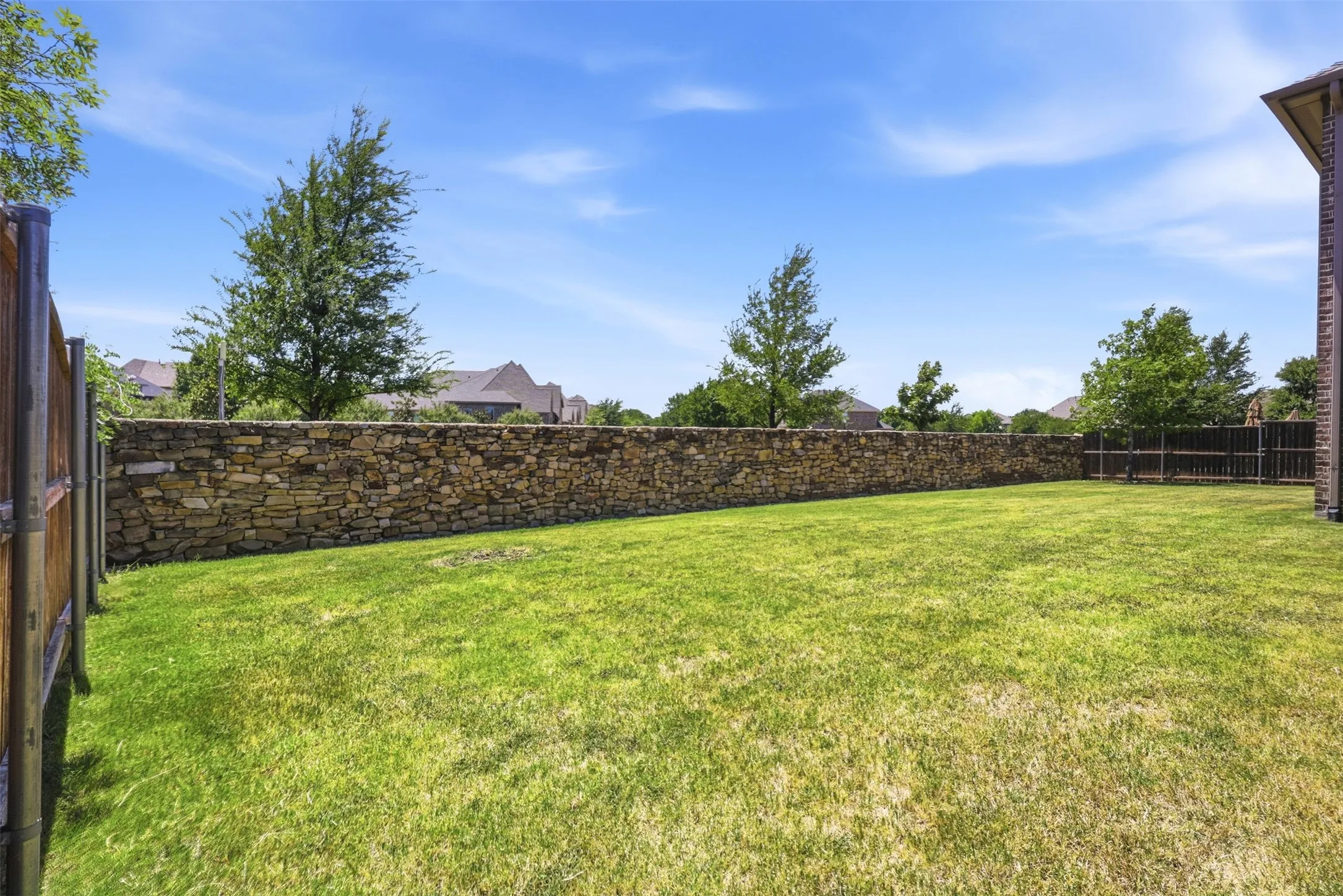 Large backyard with low maintenance stone wall