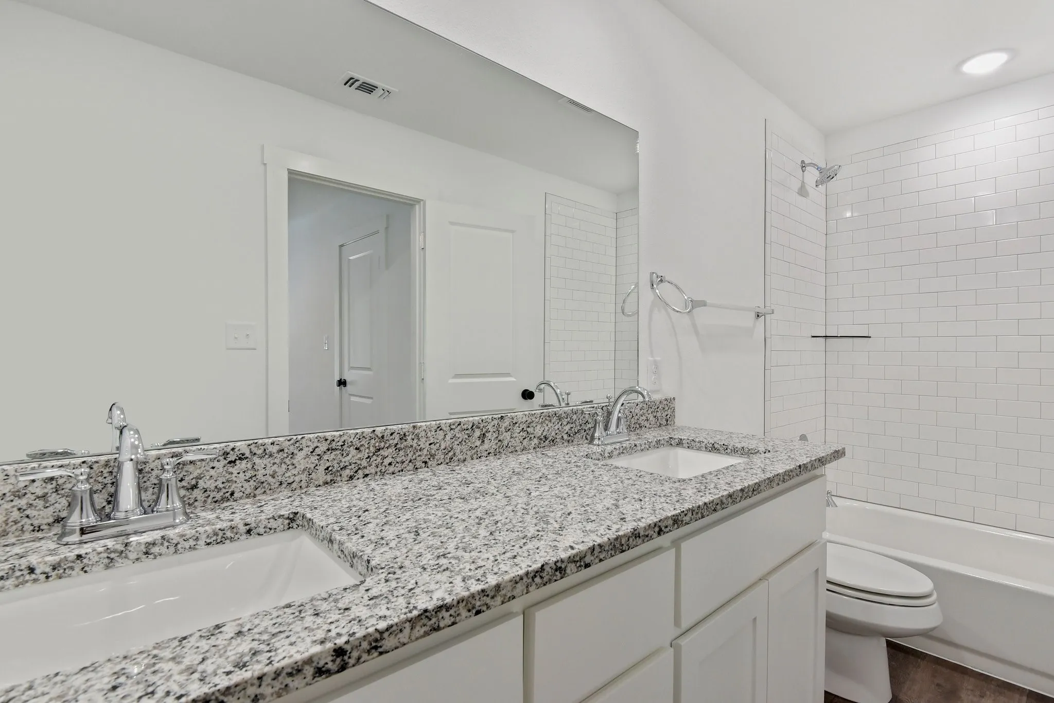 Full bath with double vanity, bathing tub / shower combination, and dark wood-style flooring