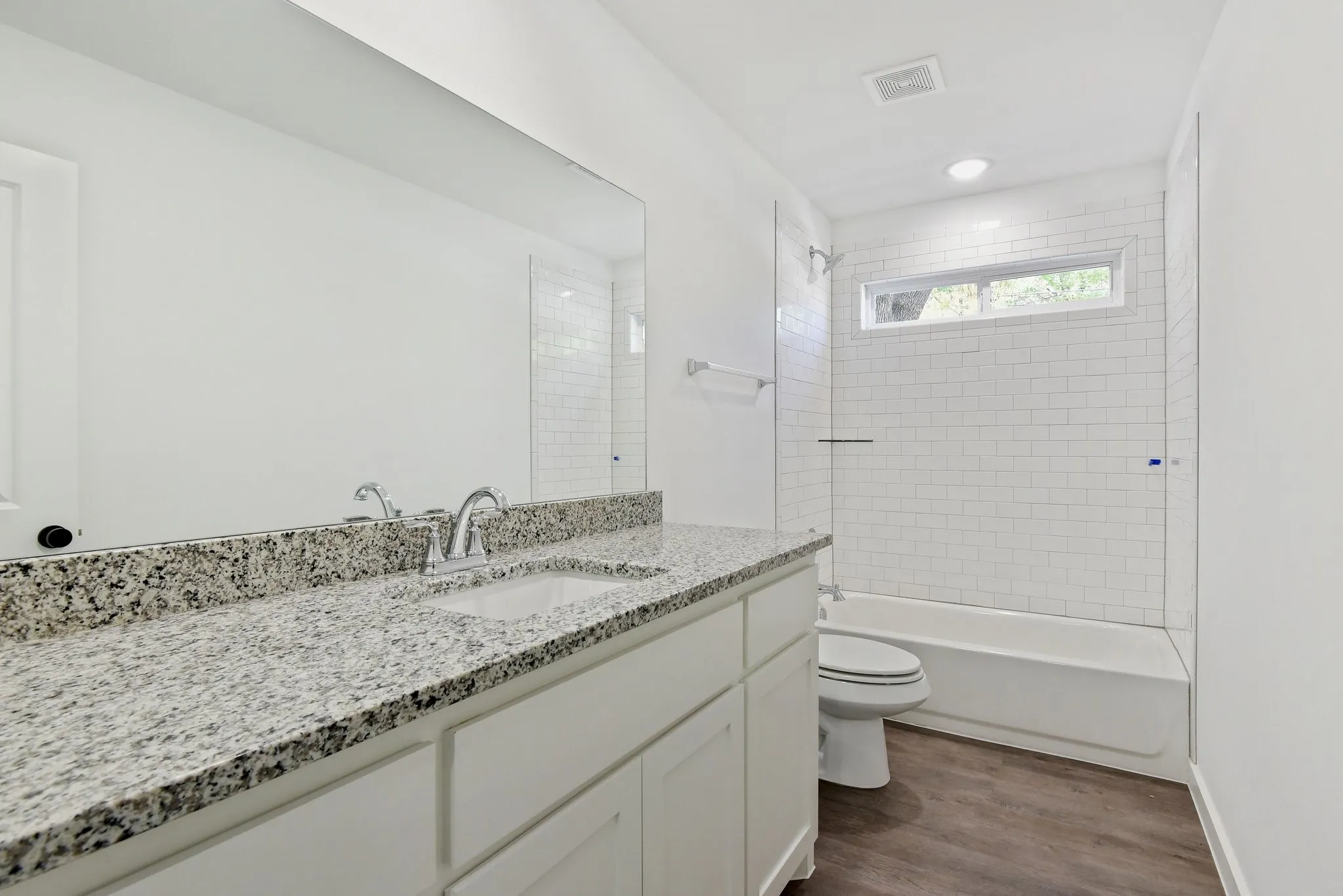 Bathroom featuring vanity, bathtub / shower combination, and dark wood-style flooring