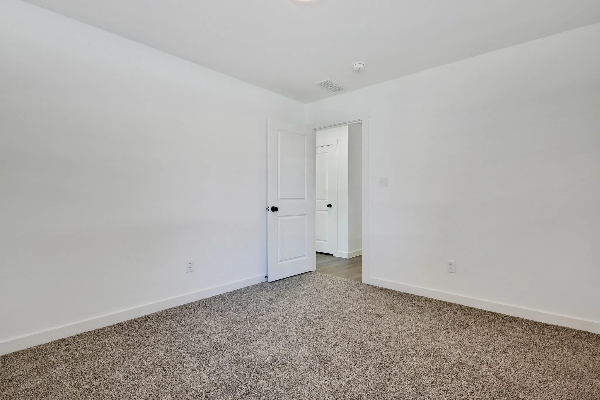 Carpeted spare room featuring baseboards