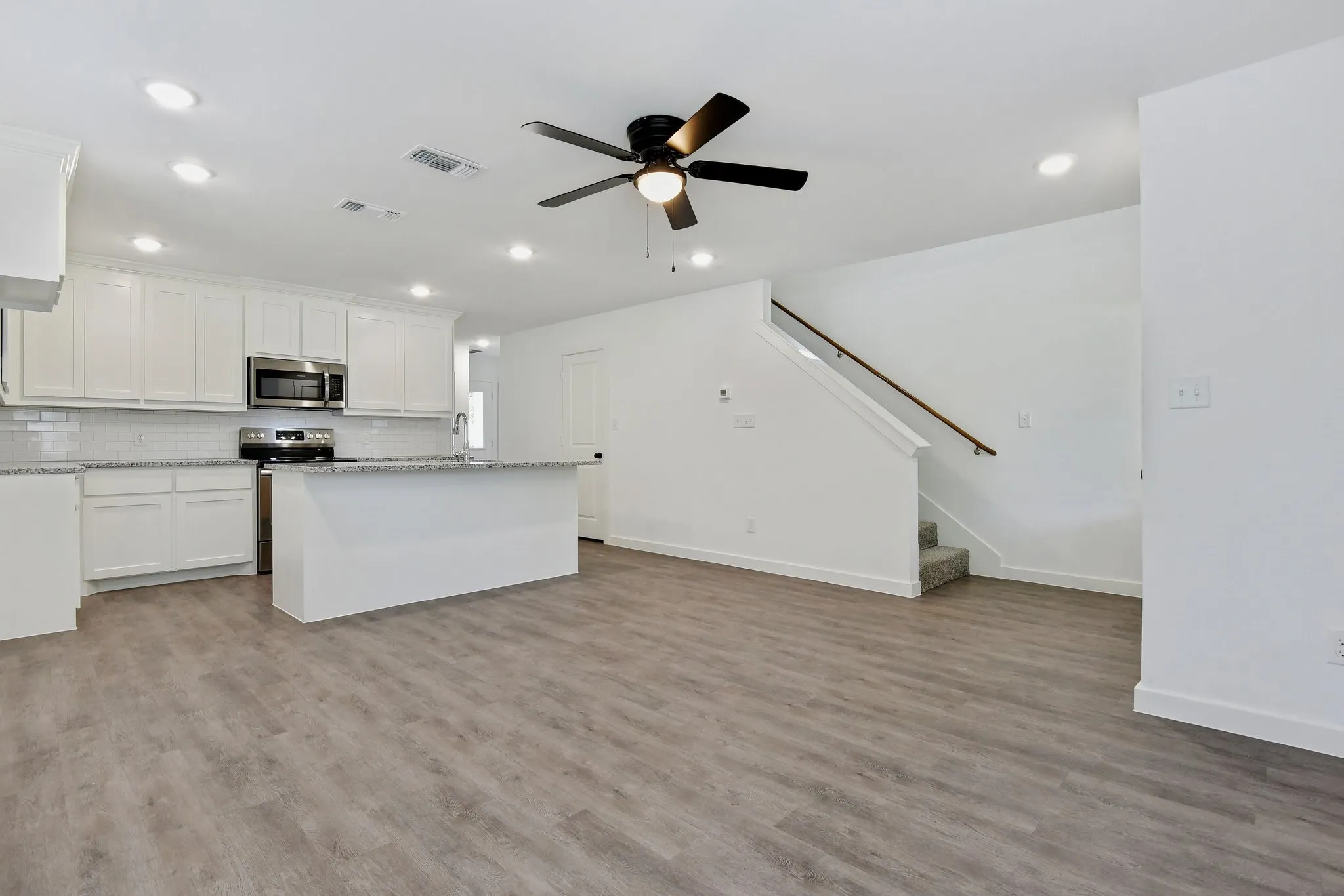 Kitchen featuring a kitchen island, white cabinets, backsplash, light wood finished floors, and recessed lighting