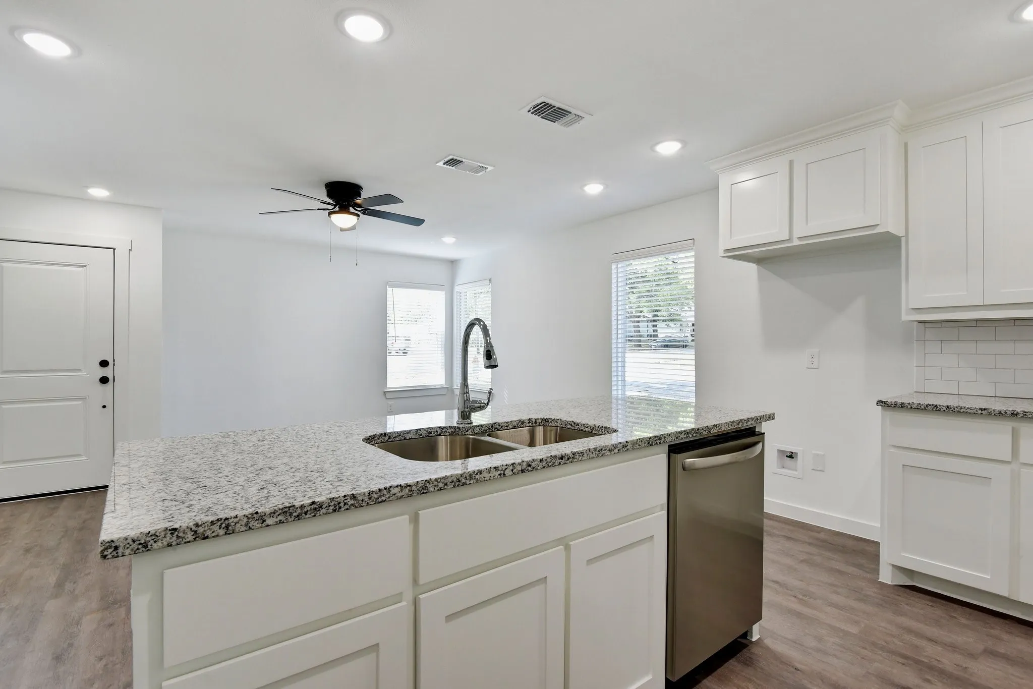 Kitchen with white cabinetry, light stone counters, recessed lighting, dishwasher, and dark wood-type flooring