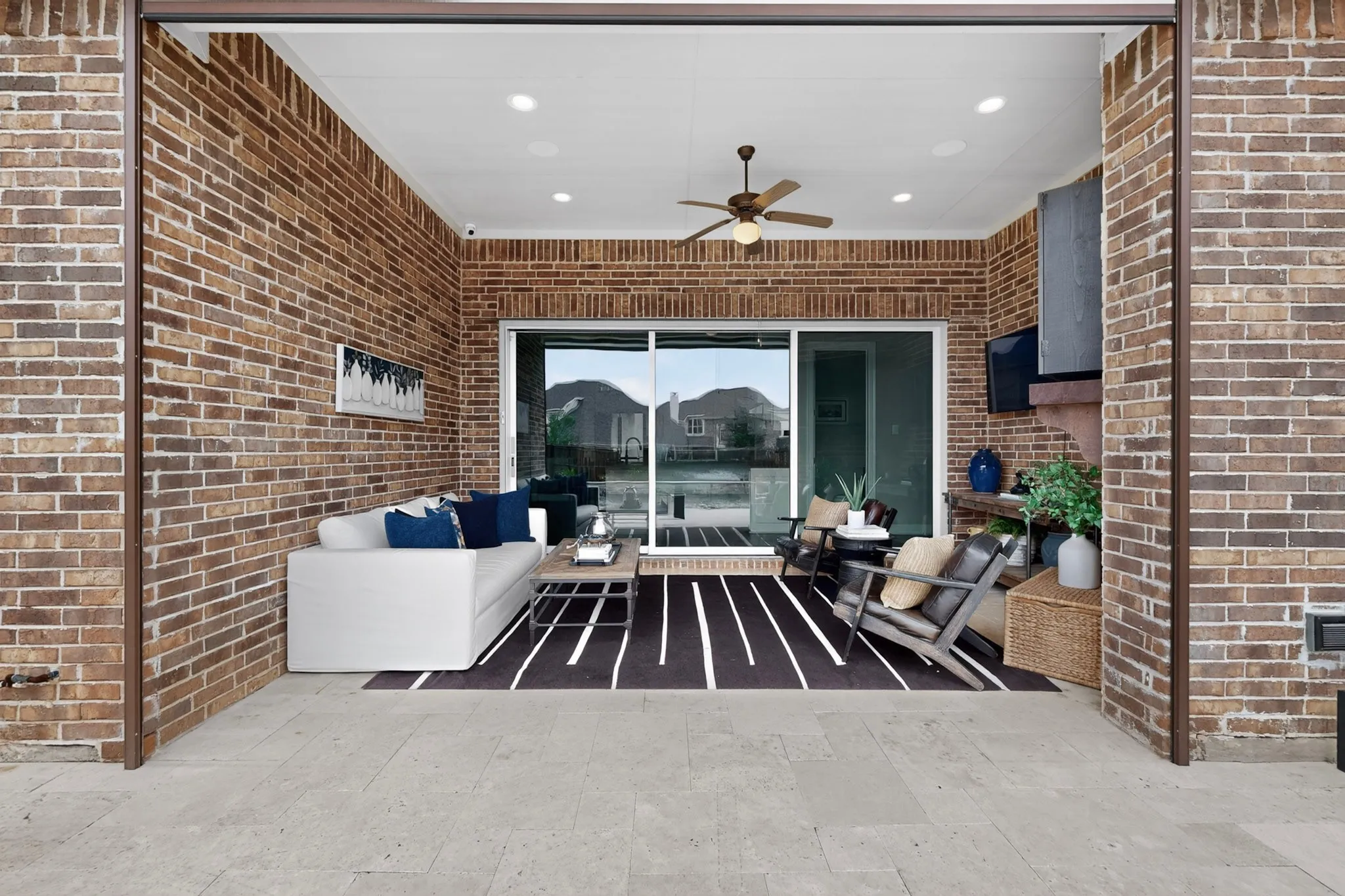 Covered patio with exposed brick walls, recessed ceiling lighting, and ceiling fan
