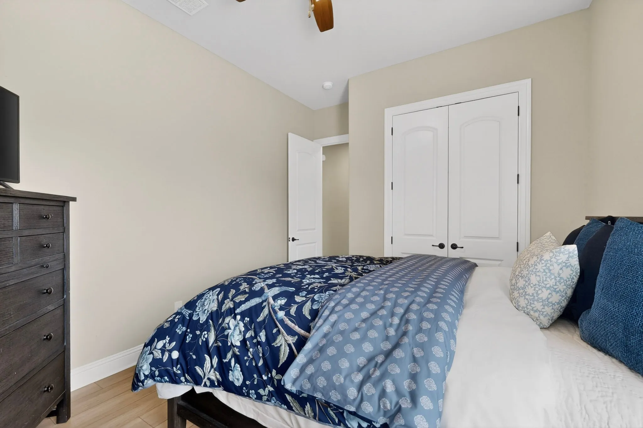 Recessed ceiling lighting, wood-finish flooring, white bi-fold closet doors with black hardware, and light neutral wall paint