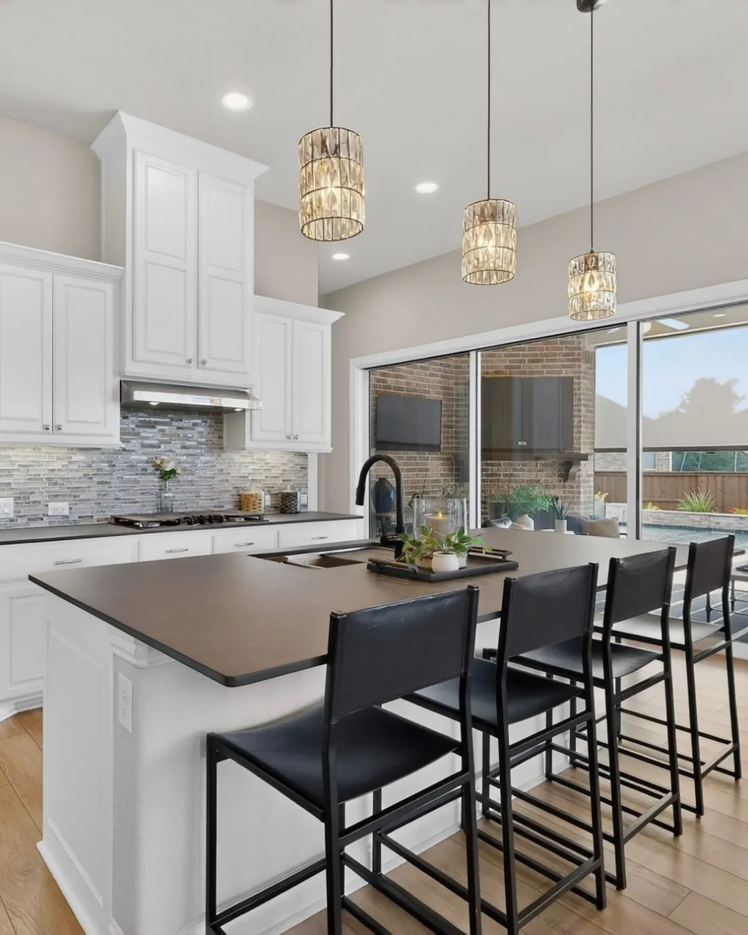 Contemporary kitchen featuring crisp white cabinetry with soft-close doors, a sleek gray quartz island countertop with waterfall edge, and integrated stainless steel appliances