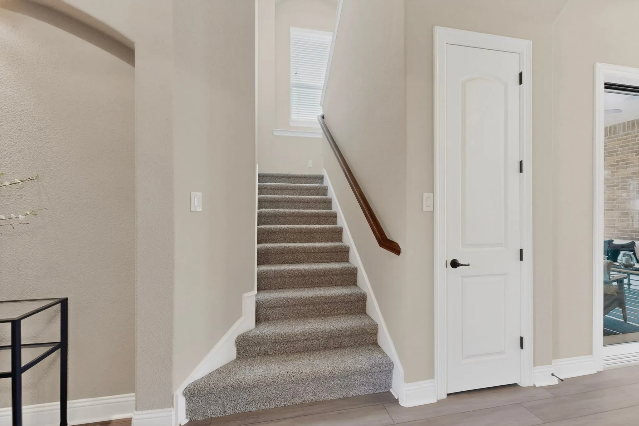 Bright staircase featuring gray carpeted treads, white painted risers, and a wood-finish handrail