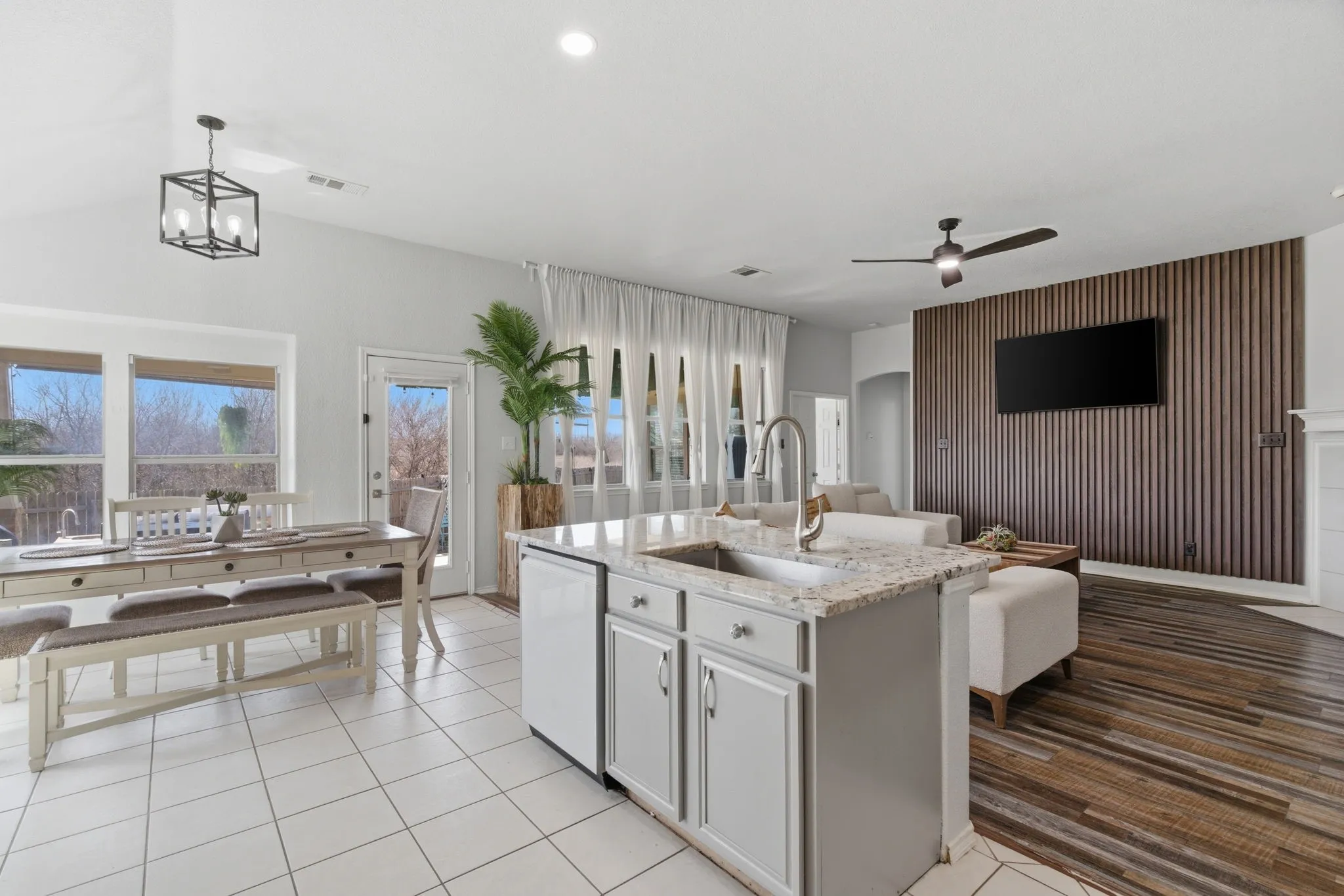 Open-concept living area featuring a kitchen island with a built-in sink, light gray cabinetry, and a light-toned countertop