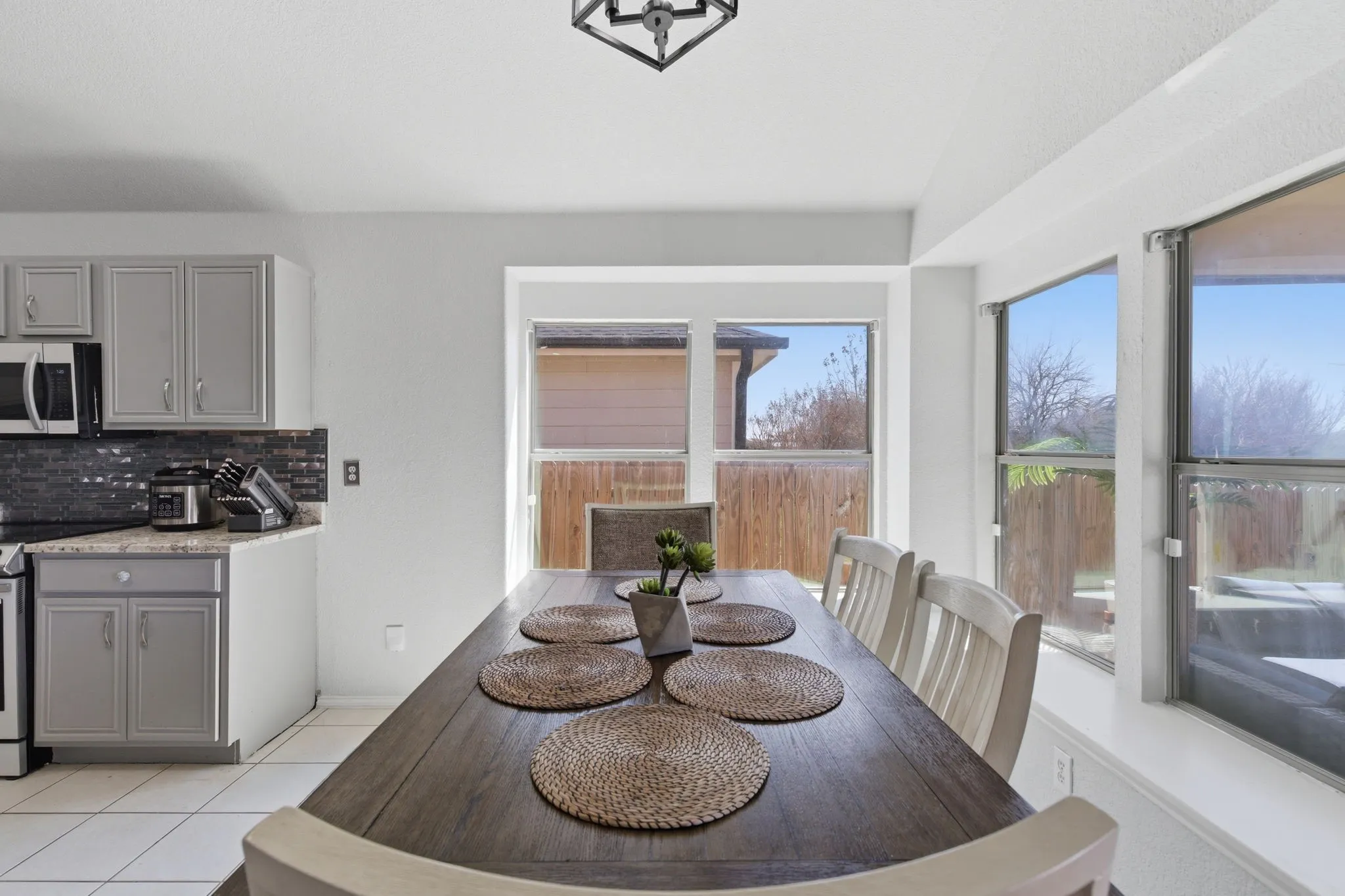 Dining area featuring a dark wood-finish table, multiple windows, and a built-in kitchen space