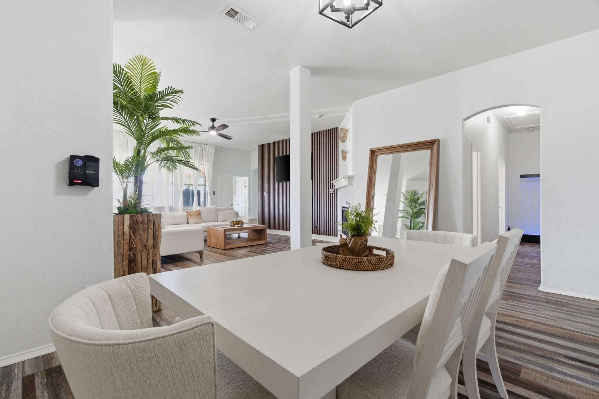 Open-concept interior featuring light-toned walls, wood-finish flooring, an arched entryway, and a geometric flush-mount ceiling light