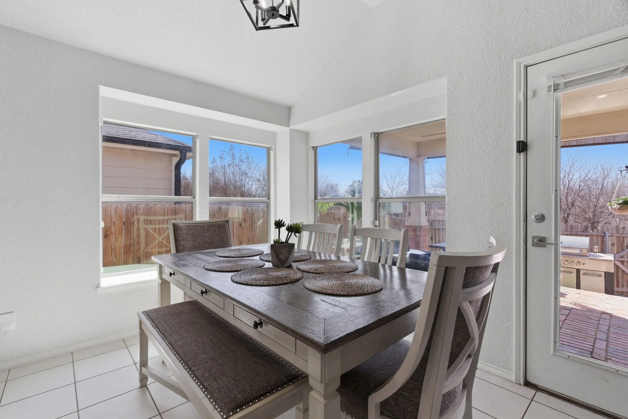 Dining area with white tile flooring and vaulted ceiling