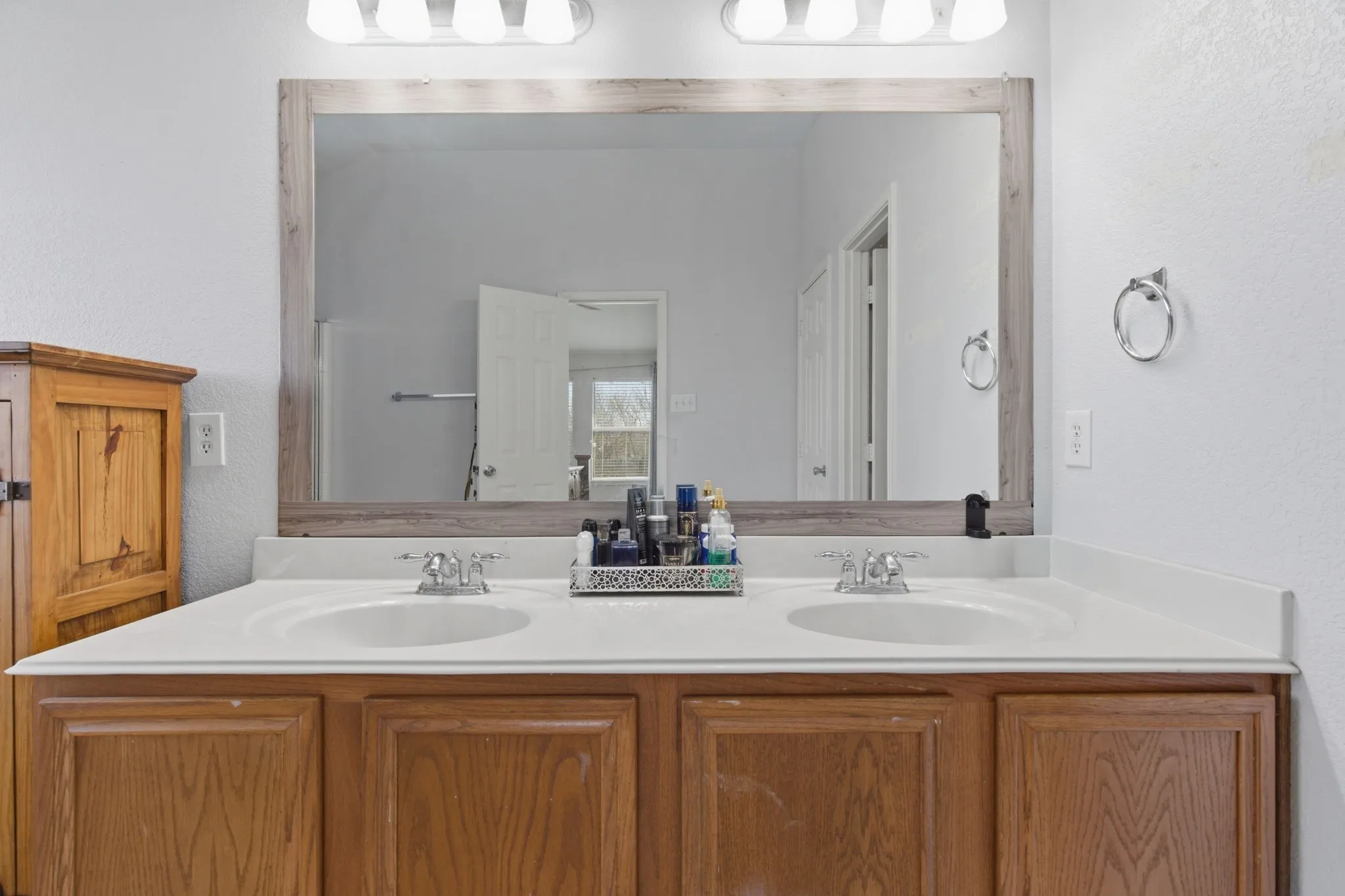 Double vanity featuring two integrated sinks, chrome faucets, and a light wood-finish cabinet