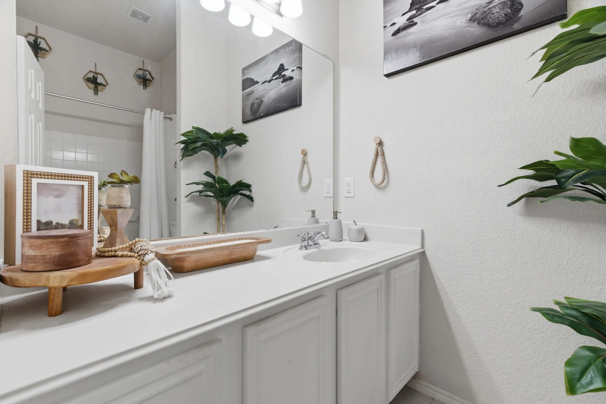 Bathroom vanity featuring a white countertop with integrated sink, chrome faucet, and white paneled cabinetry