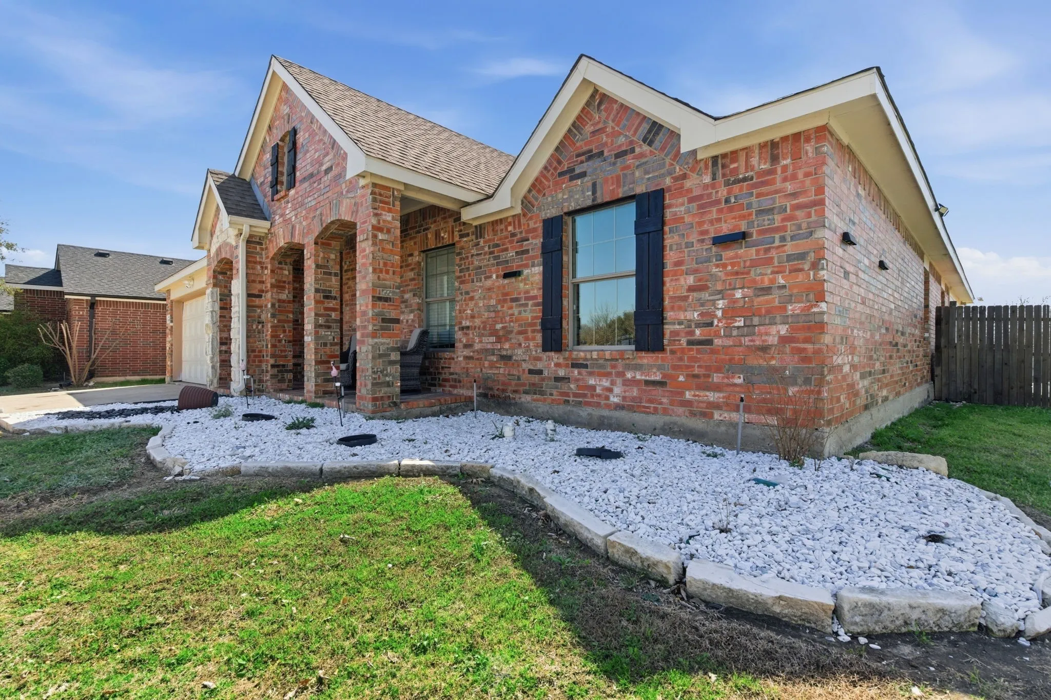 Traditional brick exterior featuring dark shutters and a covered entry with stone columns