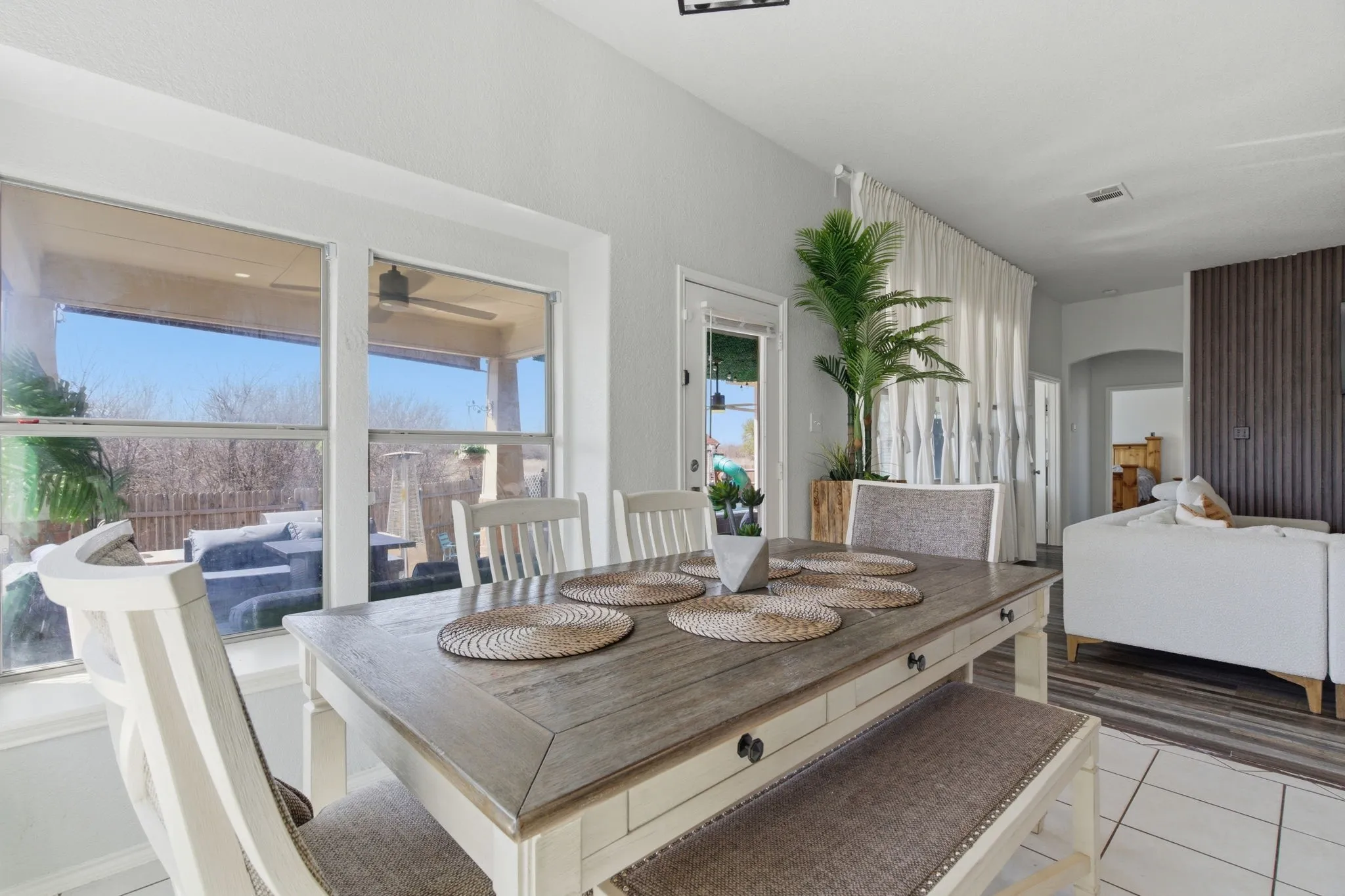Dining area featuring a large window, tile flooring, and a decorative slatted wall accent
