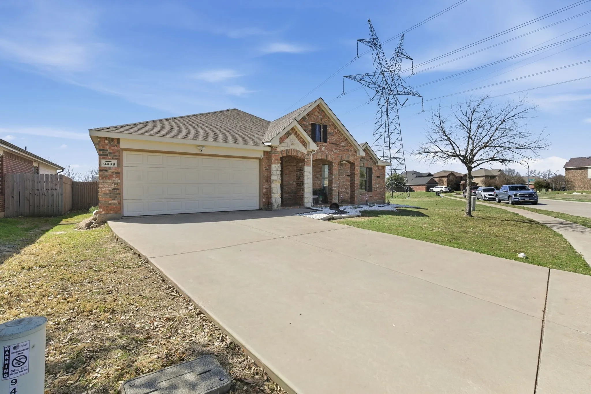 Brick facade residence featuring a front-facing attached garage, a concrete driveway, and a partially covered entry