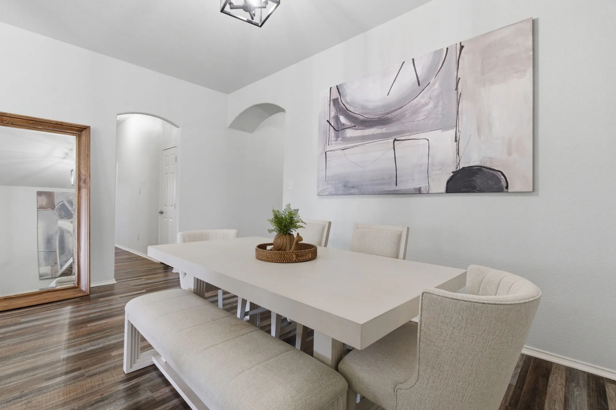 Spacious dining area featuring wood-finish flooring, light-toned walls, and an arched doorway