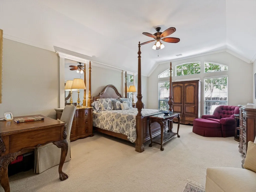 Vaulted ceiling with a ceiling fan, carpeted flooring, large arched windows, and crown molding