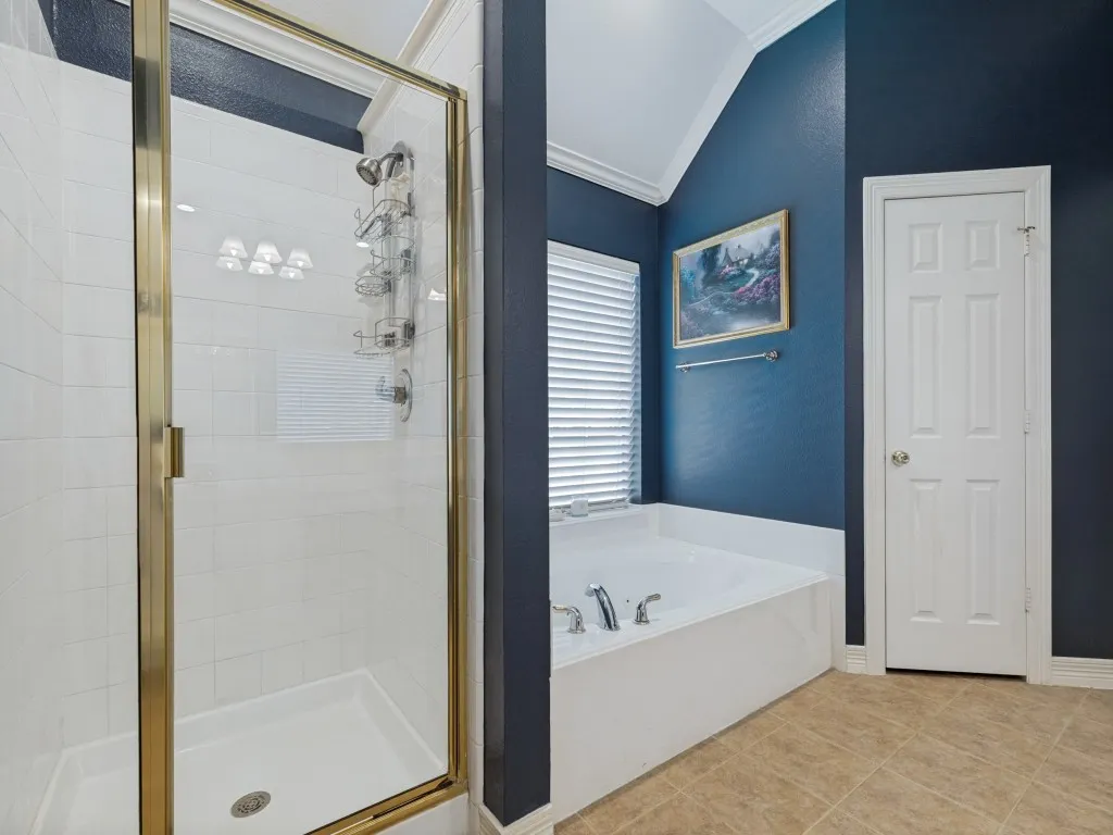 Enclosed shower with gold-tone frame, white tiled walls, and a built-in tub