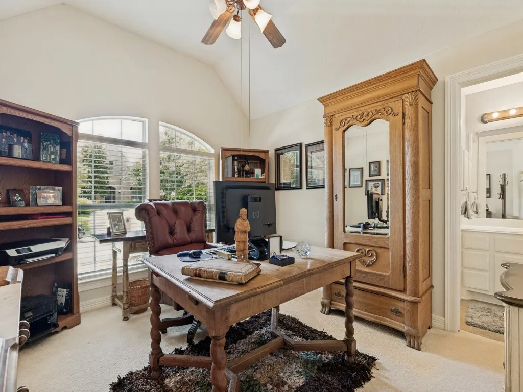Vaulted ceiling with a ceiling fan, arched window, and carpeted flooring
