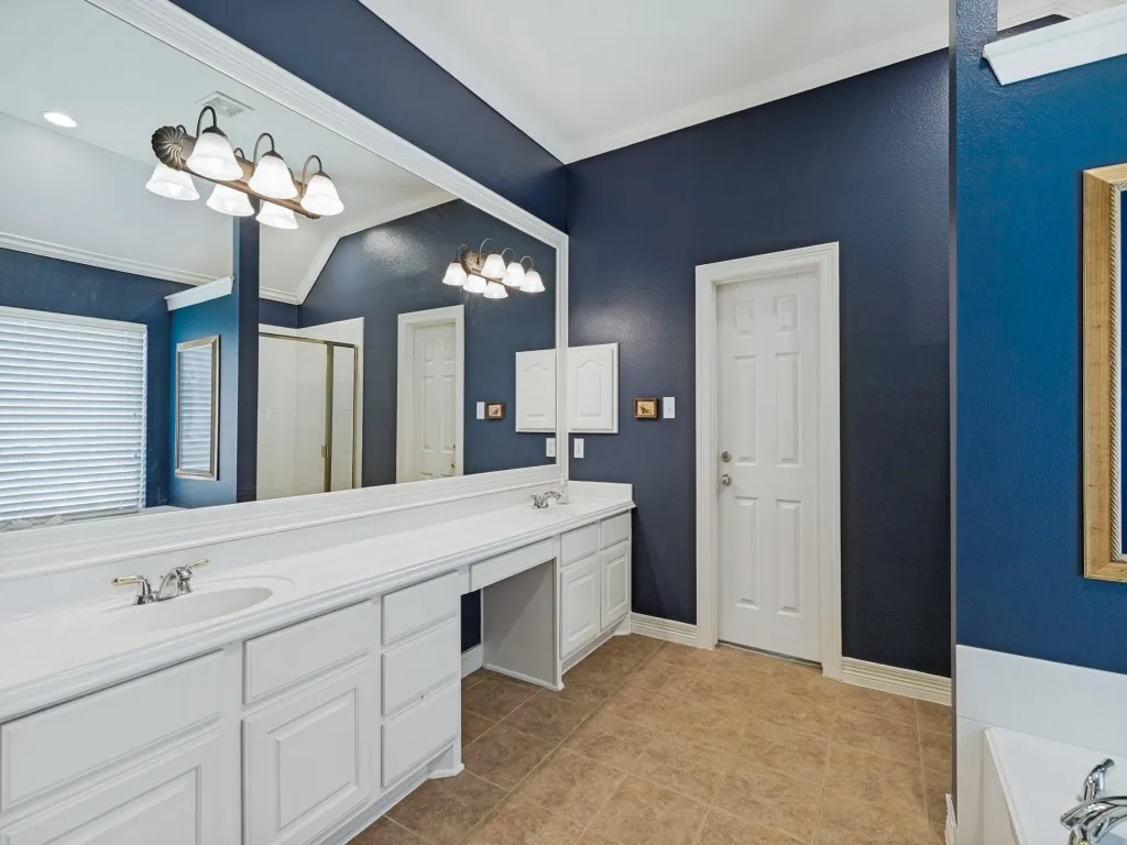 Extended vanity with dual integrated sinks, white cabinetry, and ample counter space