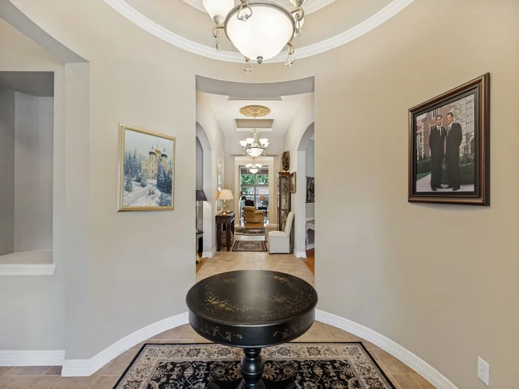 Archway entrance with decorative ceiling trim and a chandelier