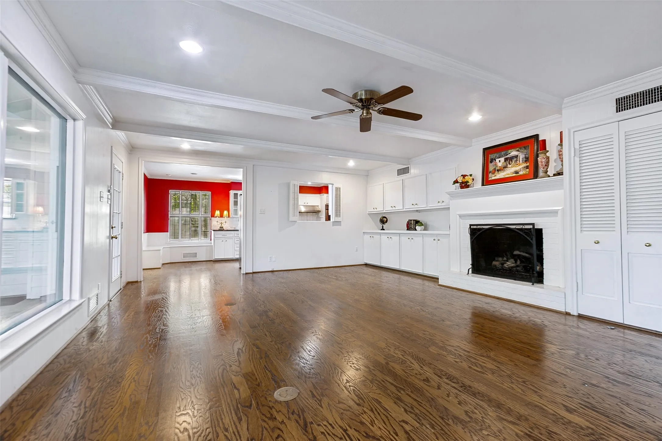Wood flooring, built-in cabinets, louvered doors to shelving.