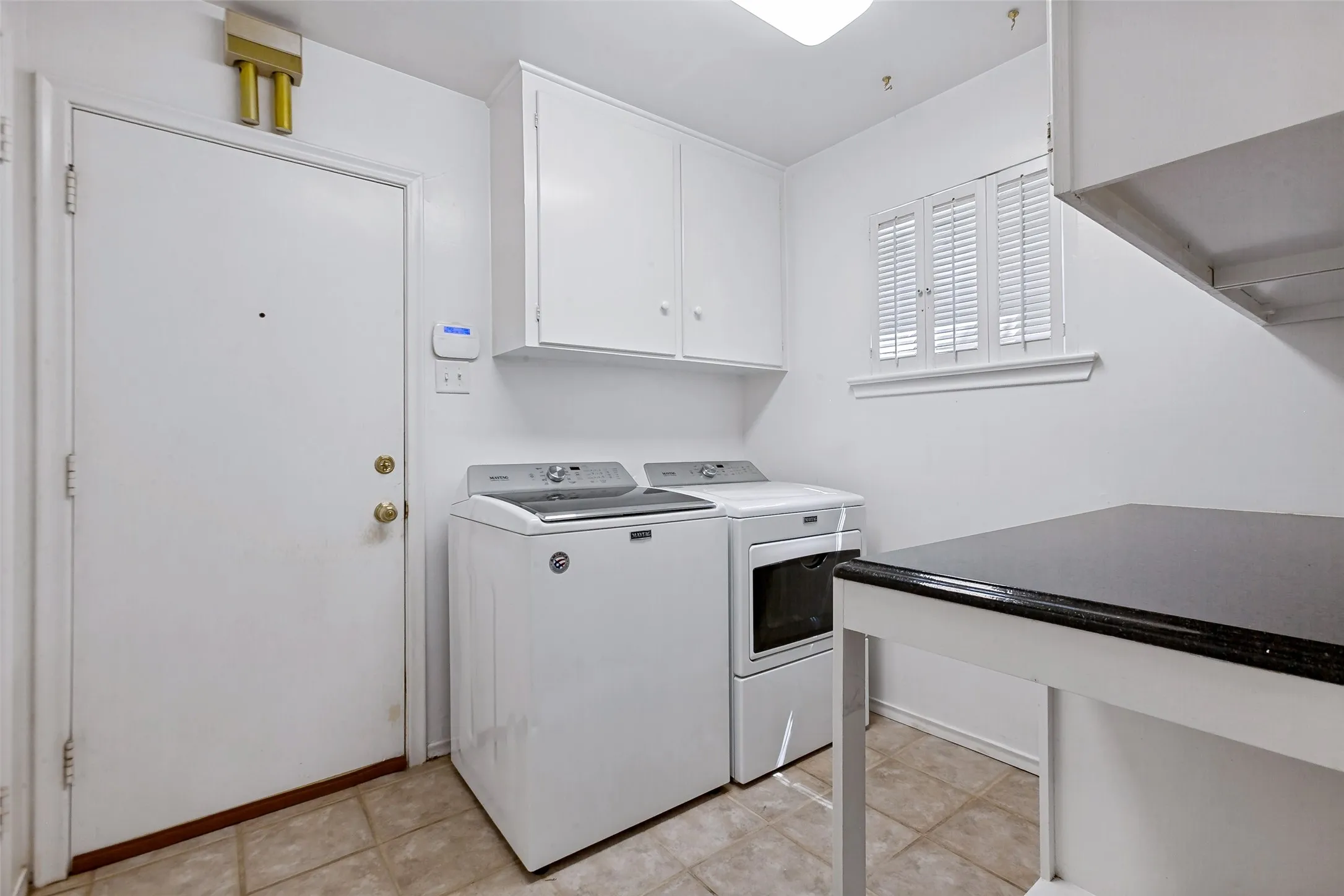 Dedicated laundry area features built-in cabinets, laundry-folding countertop, and a double door to the pantry. Washer and dryer remain with the property.