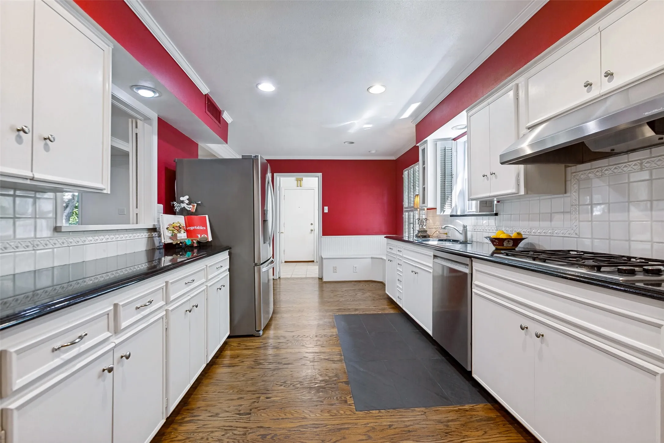 Galley kitchen featuring white cabinetry, a stainless steel refrigerator, and a gas cooktop.