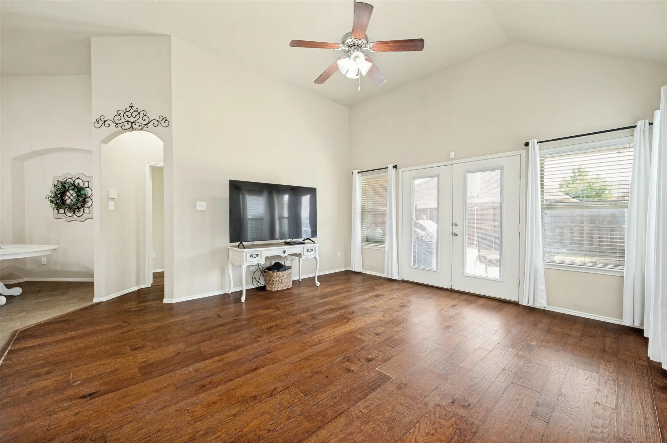 Spacious living area featuring vaulted ceilings, wood-finish flooring, and arched doorways