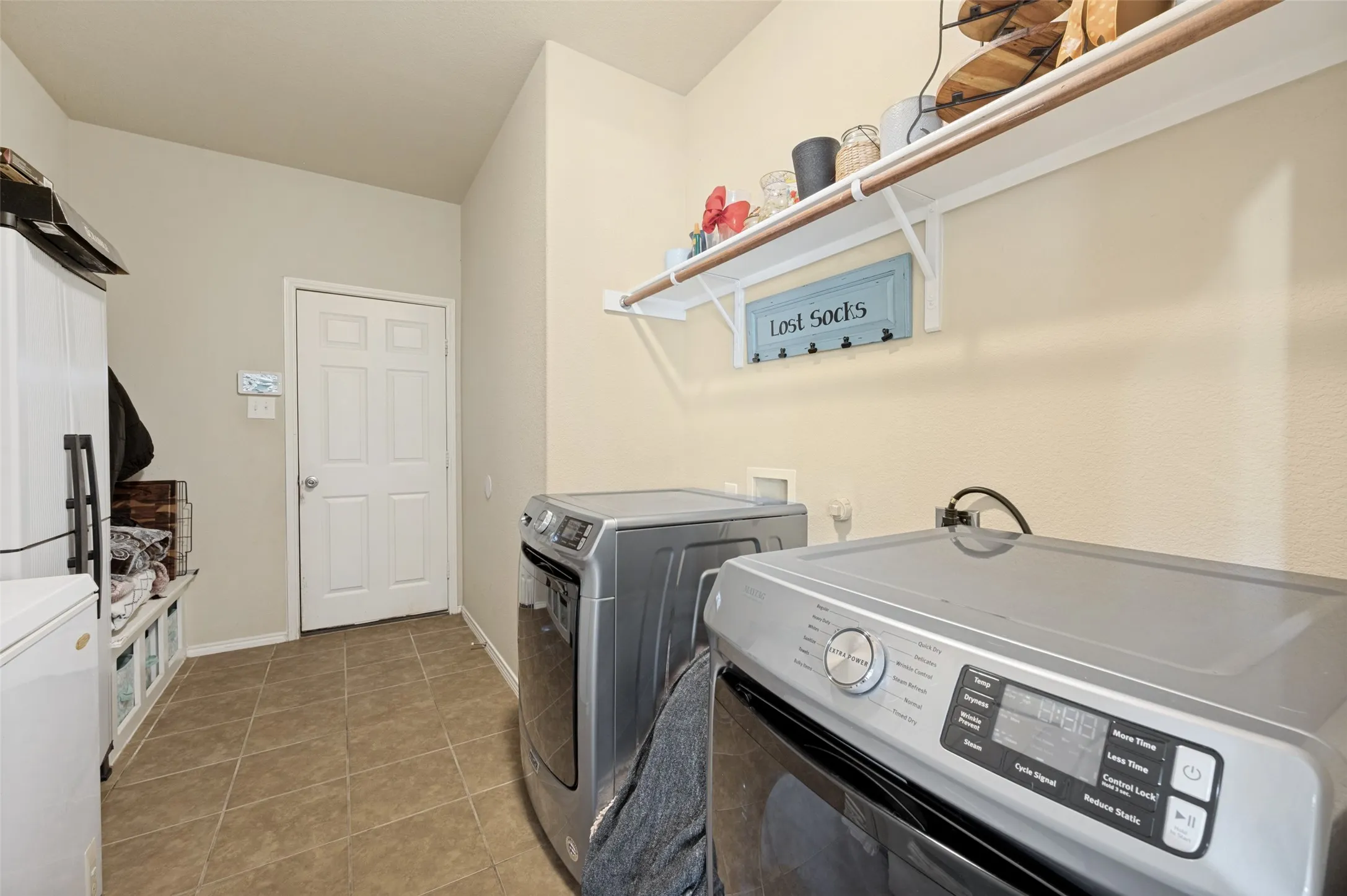 Functional utility room featuring neutral wall tones, tile flooring, and a white paneled door