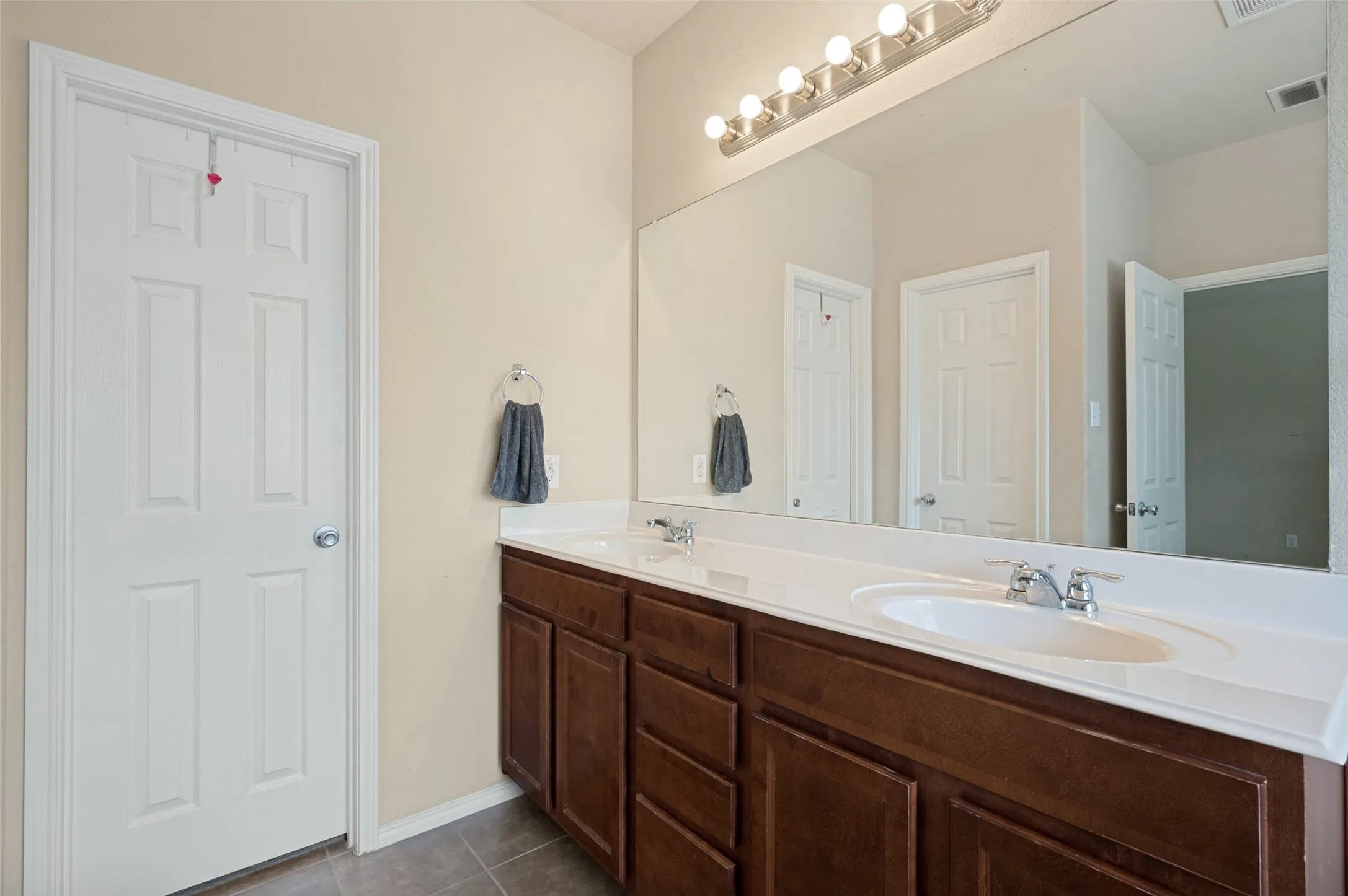 Dual vanity featuring wood-finish cabinetry, integrated white sinks, and chrome faucets