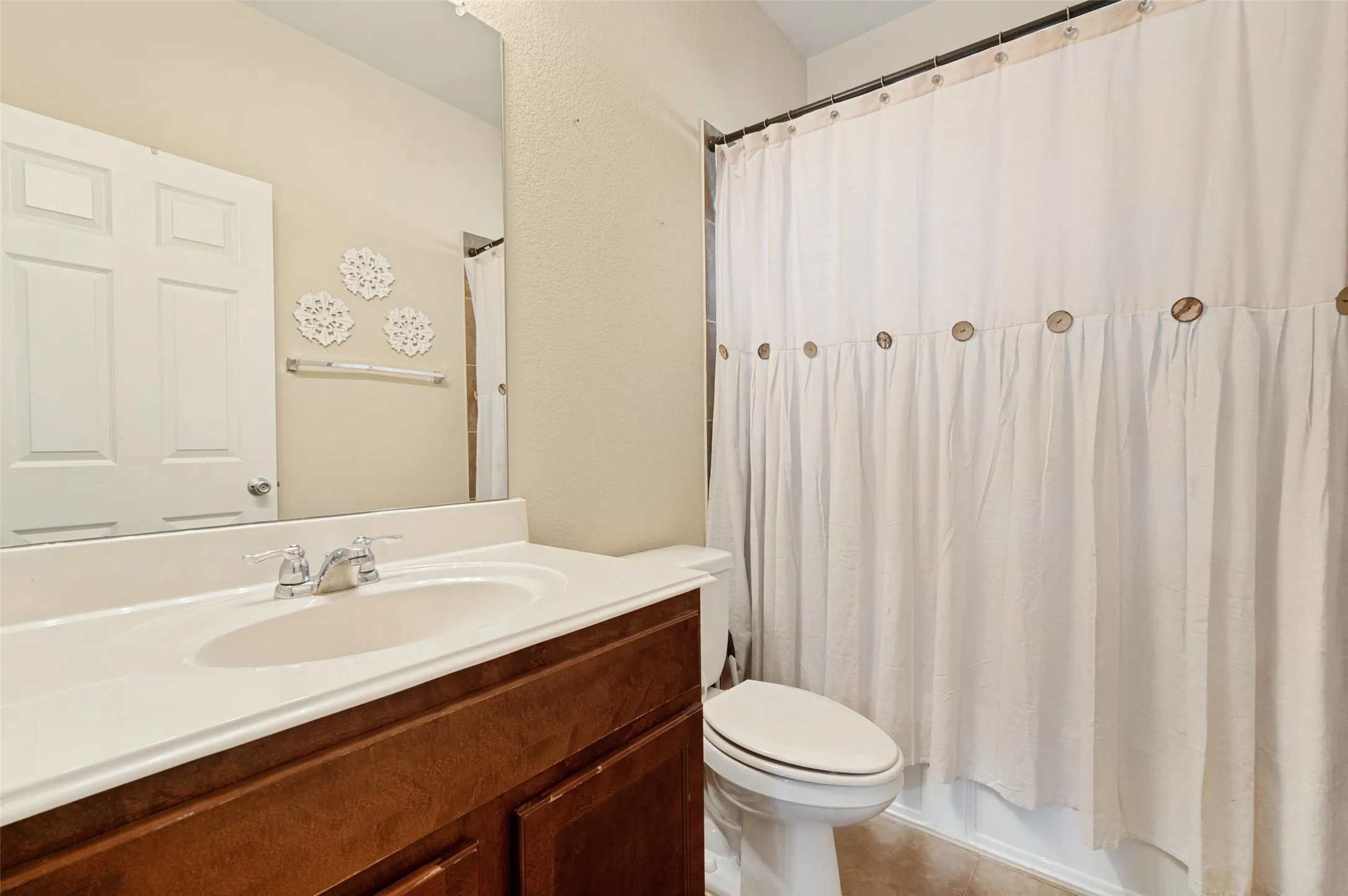 Bathroom featuring a dark wood-finish vanity with an integrated white sink and countertop, chrome faucet, and a large wall-mounted mirror