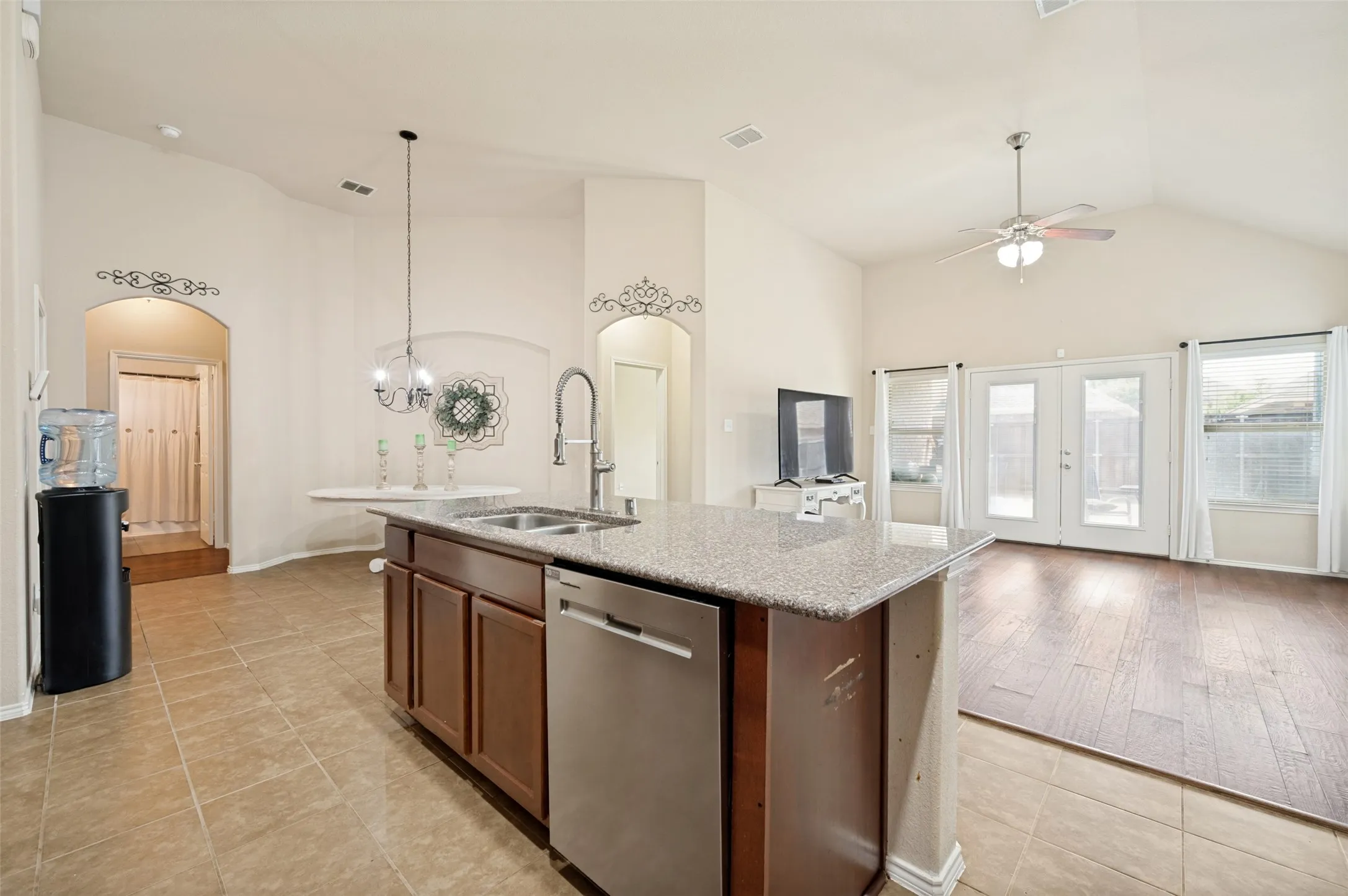 Kitchen island featuring a double-basin sink, stainless steel dishwasher, and a stone-finish countertop
