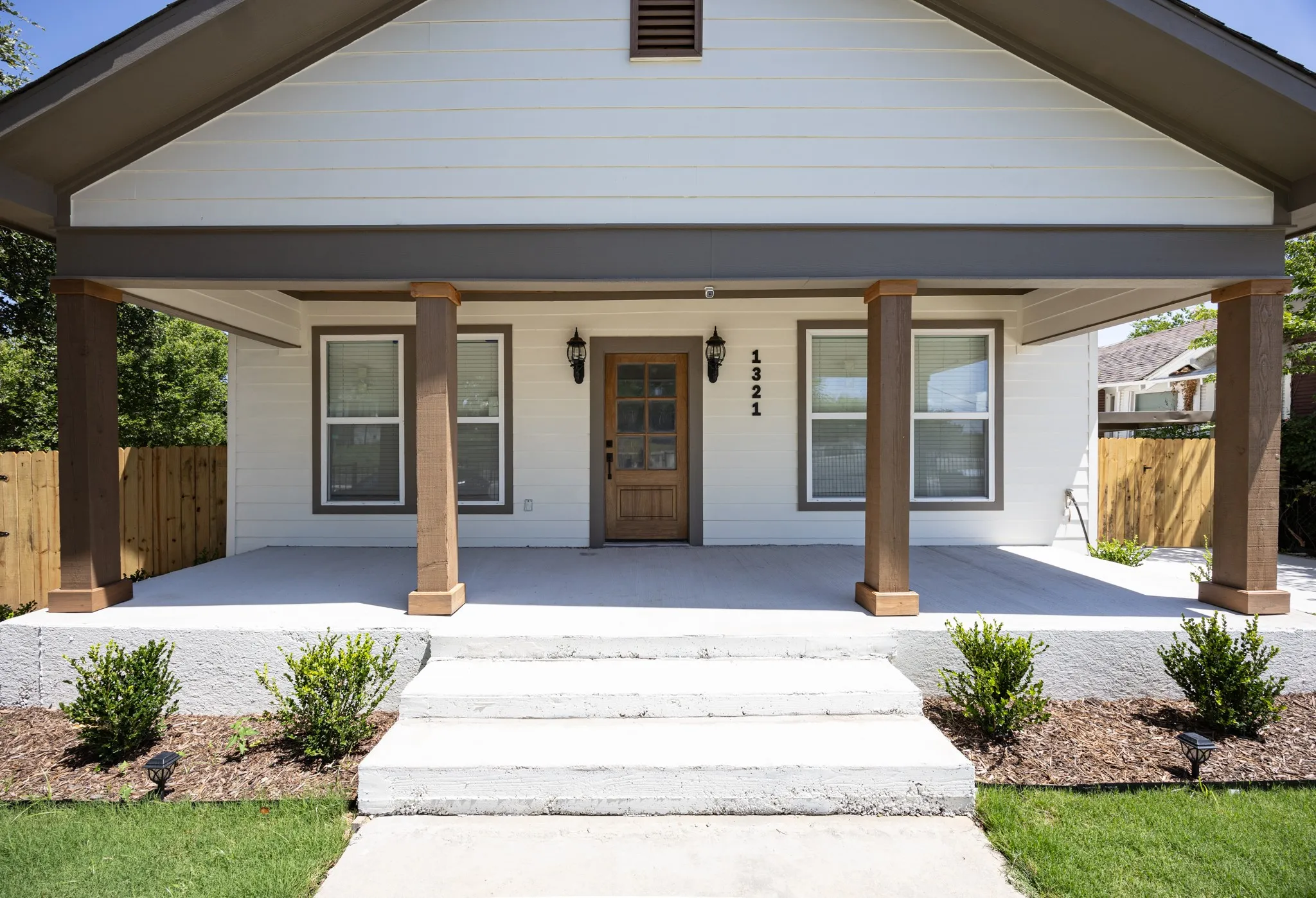 White horizontal siding exterior with a covered porch featuring four wood-finish support columns