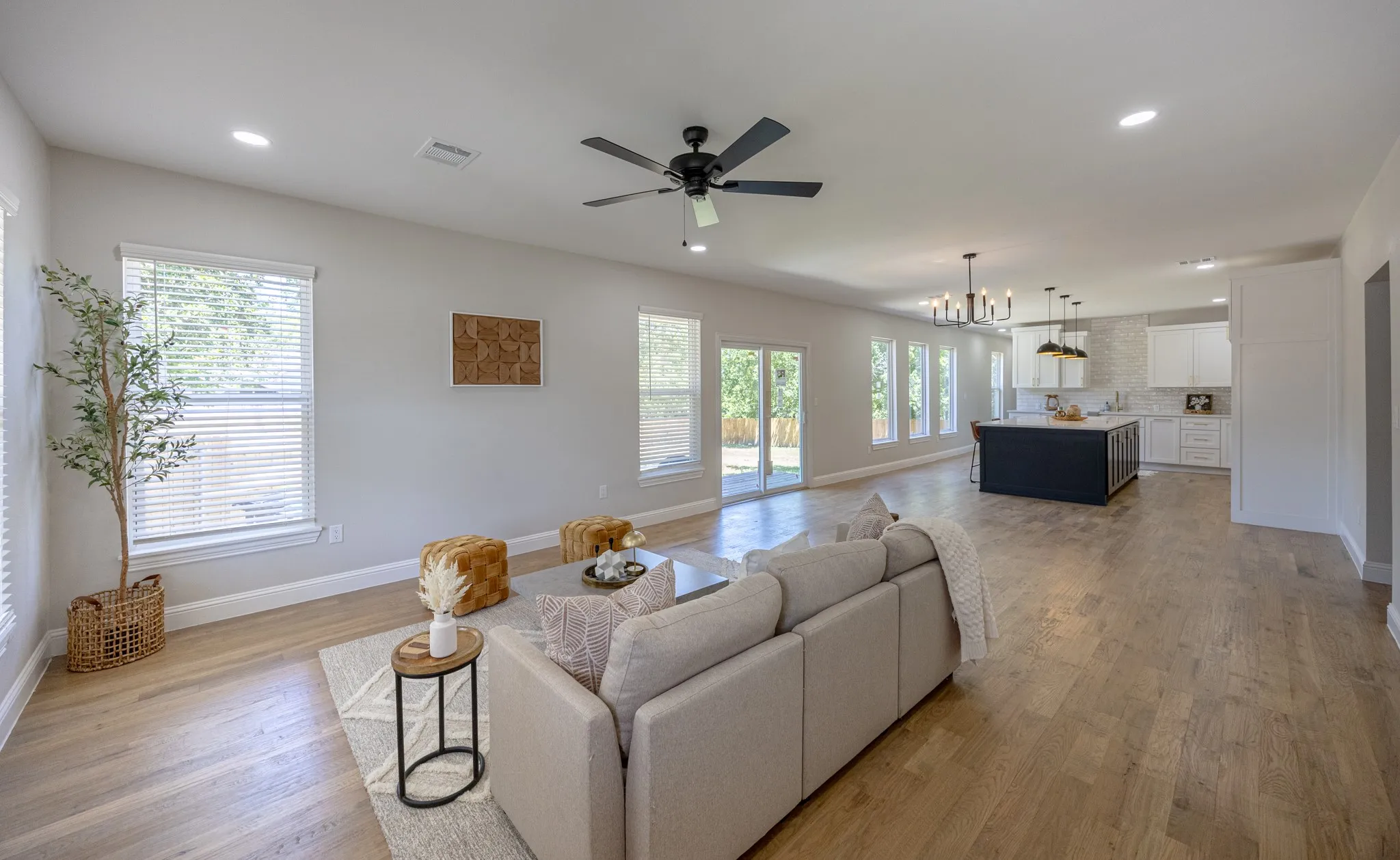 Spacious open-concept living area featuring light wood-finish flooring, recessed lighting, and a ceiling fan