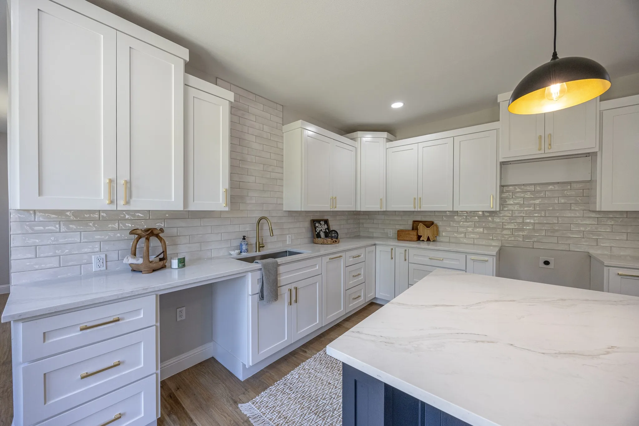 Kitchen featuring white shaker-style cabinetry, light subway tile backsplash, and a large central island with a white-patterned countertop