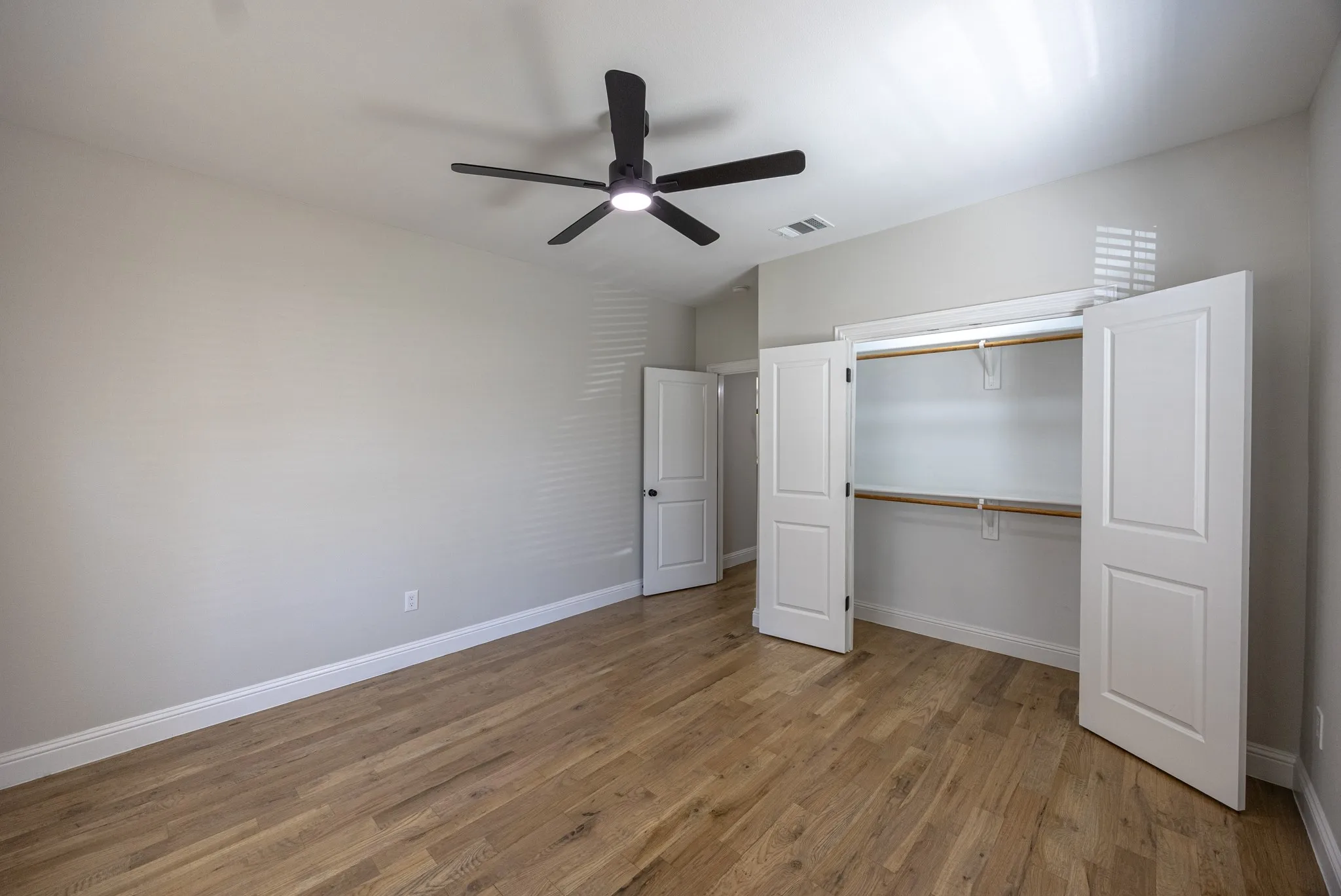 Spacious room featuring wood-finish flooring, light gray walls, and white baseboards