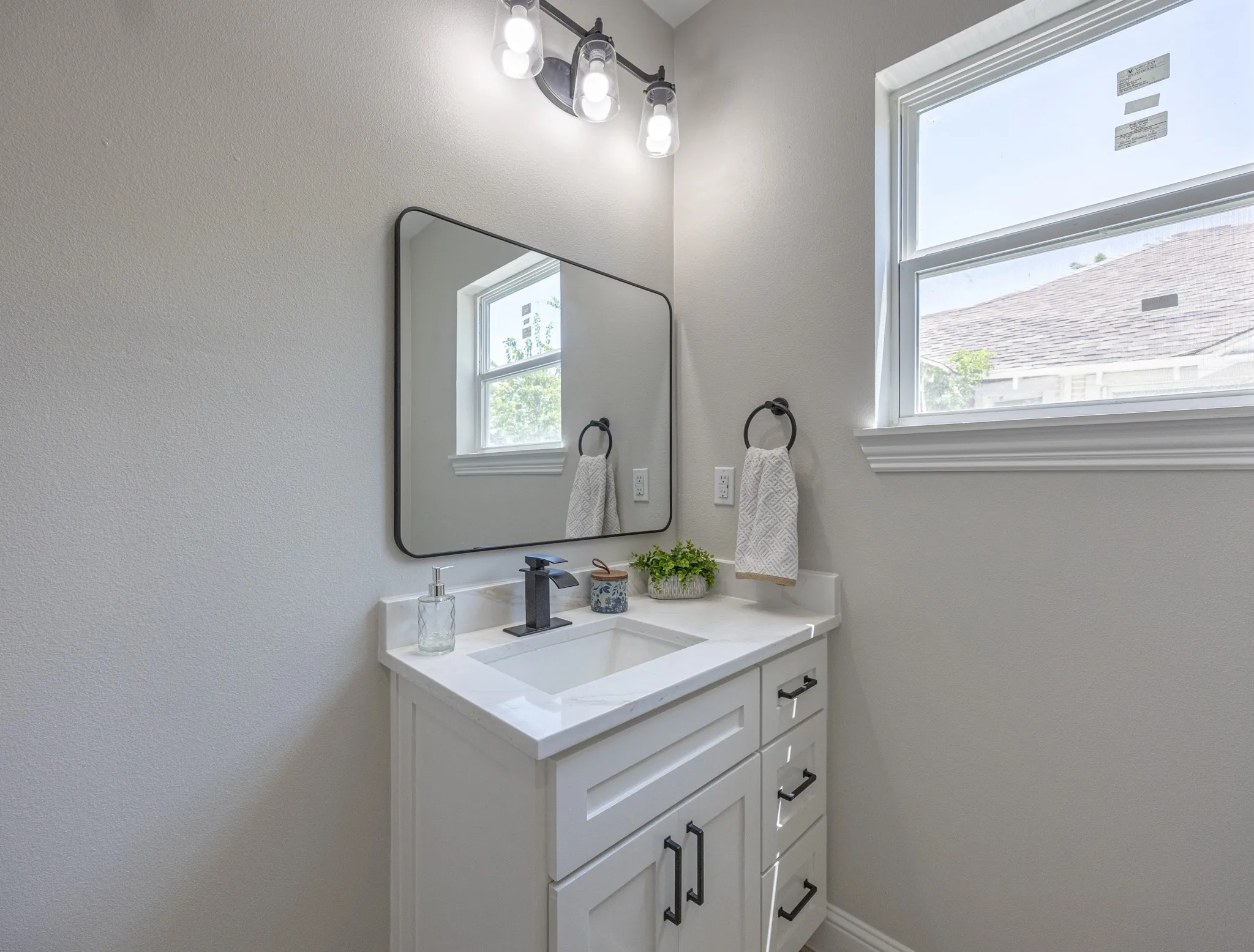 Bathroom vanity featuring a white shaker-style cabinet, integrated sink, and white countertop