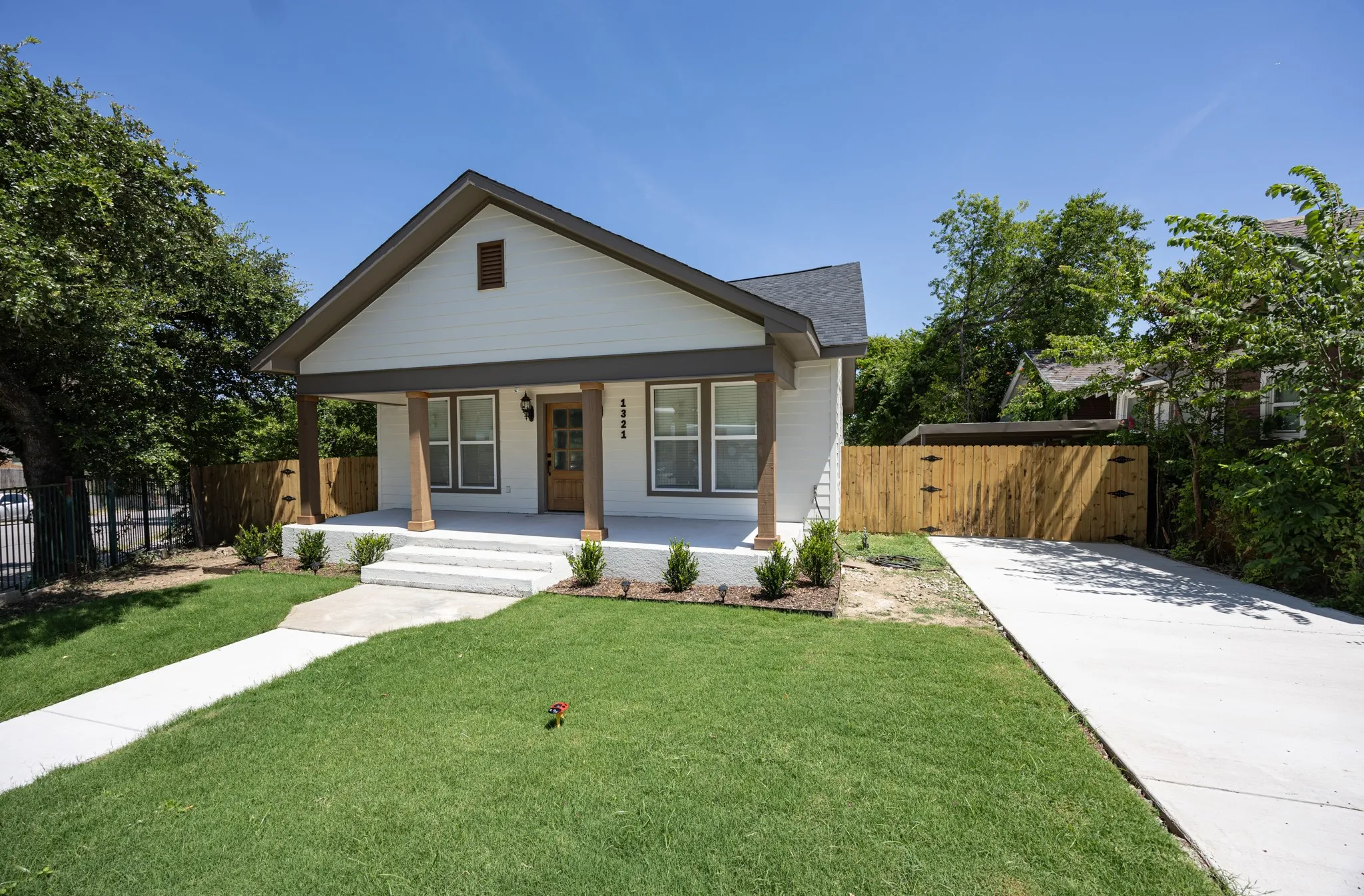 Modern farmhouse-style facade featuring white siding, a dark gray roof, and a covered porch with wood-wrapped columns