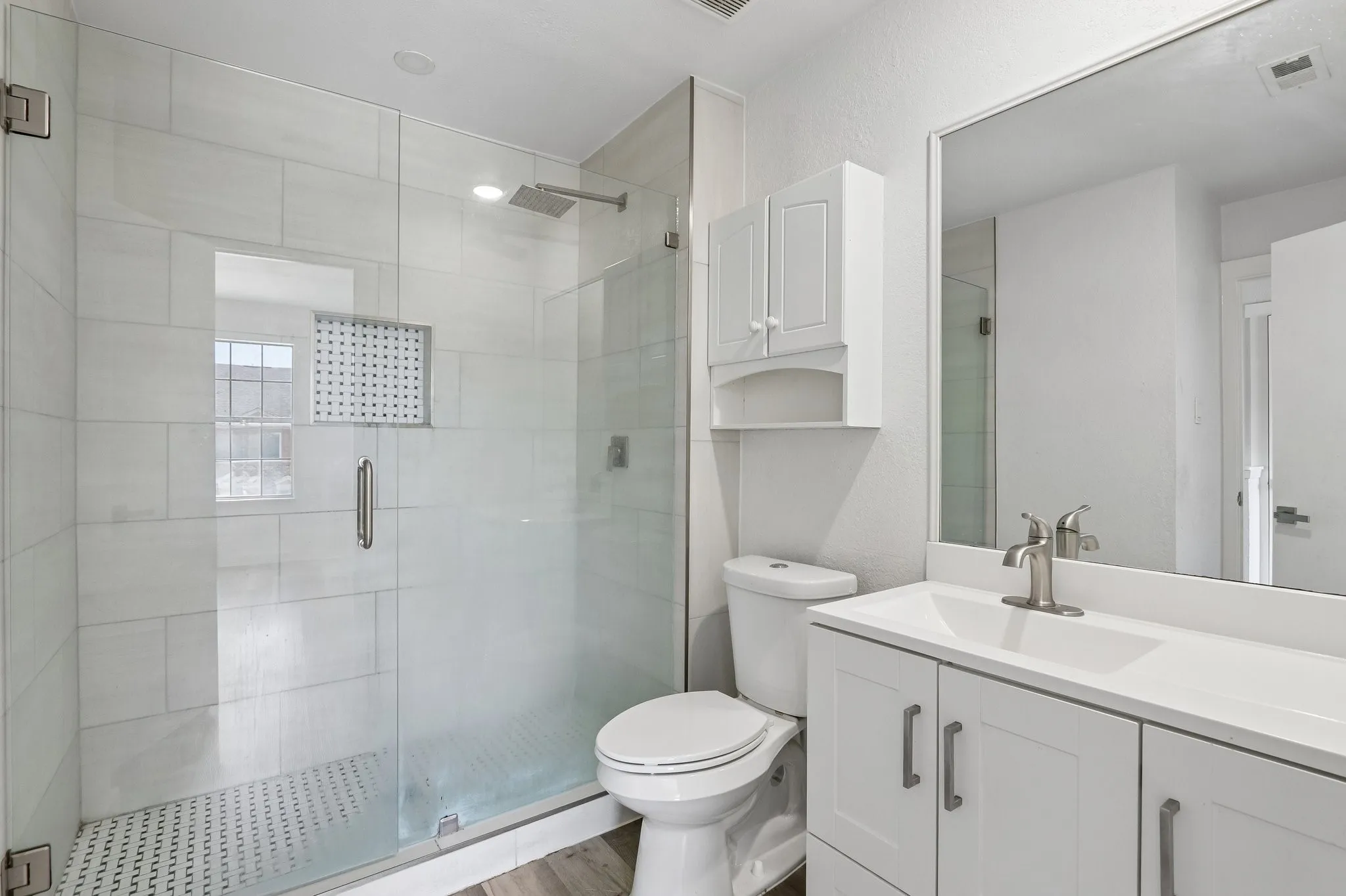 Shower with glass enclosure, white subway tile surround, and built-in niche