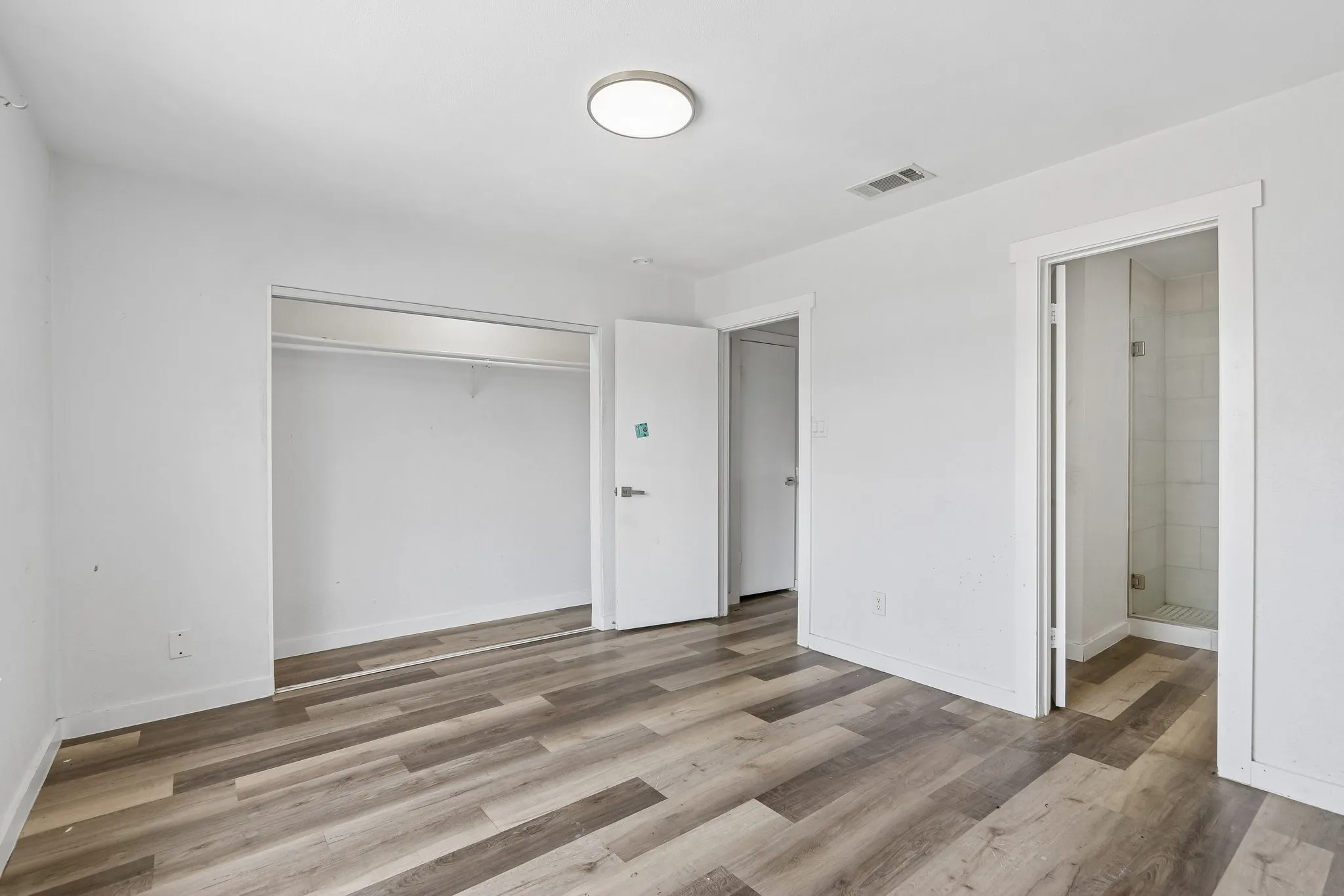 Room featuring wood-finish flooring, a built-in closet, and white walls