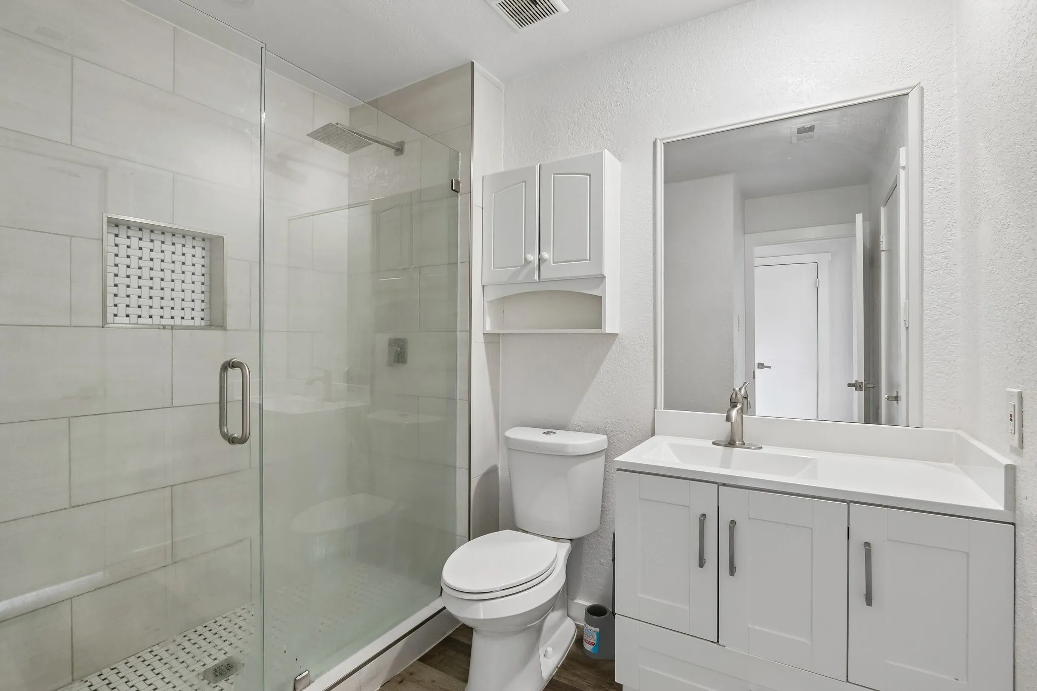 Contemporary bathroom featuring a glass-enclosed shower with a rainfall showerhead, white subway tile surround, and a mosaic-tiled shower niche