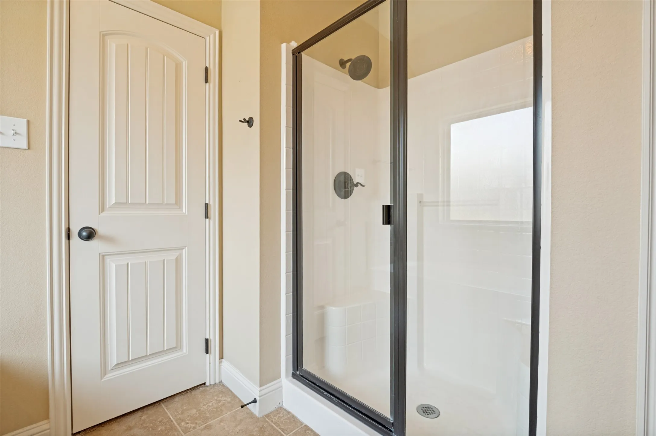 Walk-in shower with dark-framed glass enclosure, integrated bench seating, and dark-finish fixtures