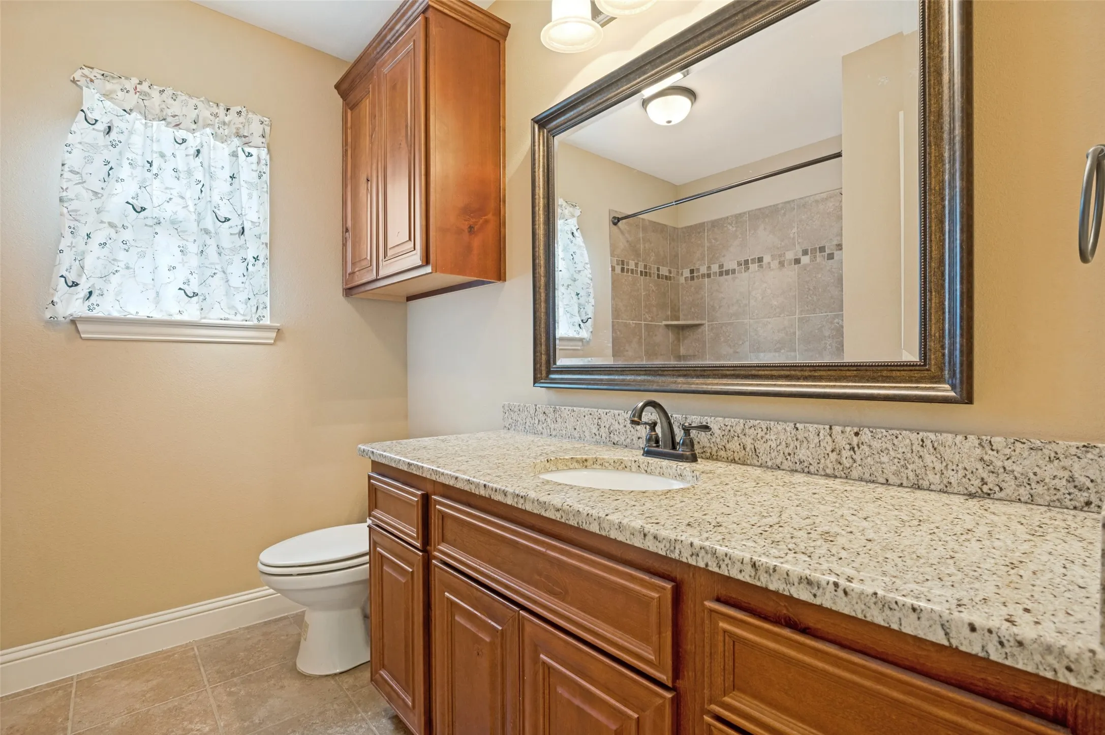 Bathroom vanity featuring a speckled countertop, undermount sink, and dark bronze faucet