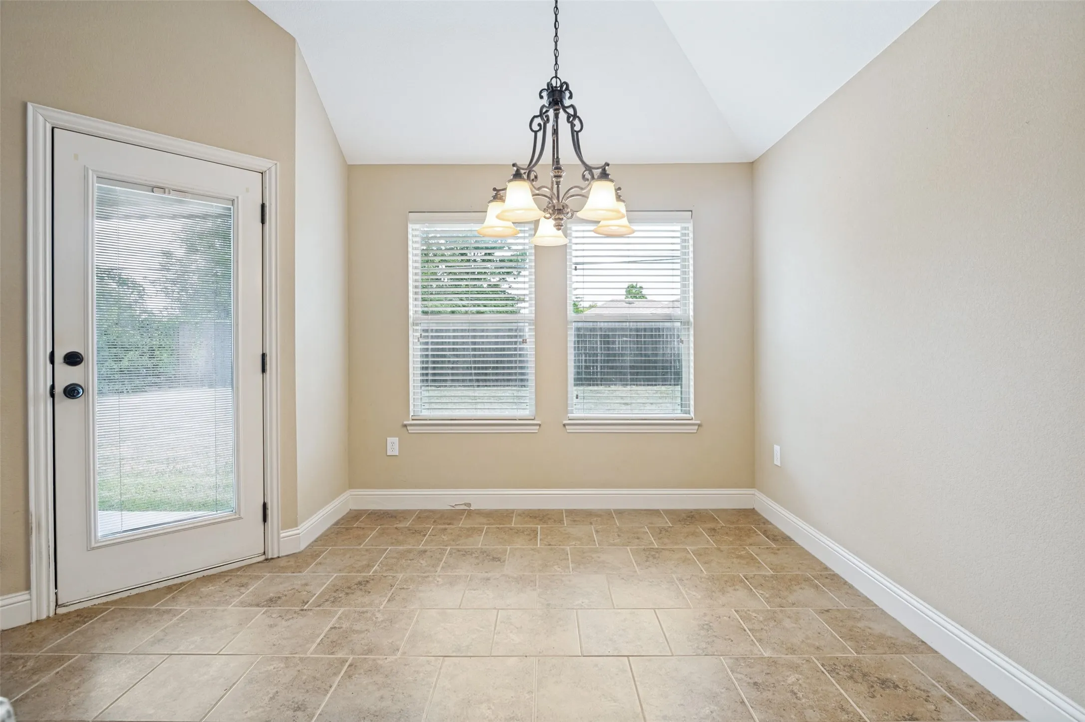 Dining area featuring vaulted ceilings, a decorative chandelier, and ceramic tile flooring