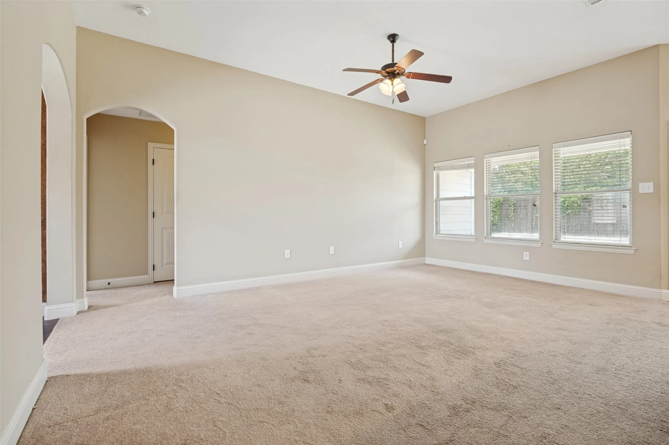 Spacious interior room featuring neutral-toned carpet flooring and light-colored walls