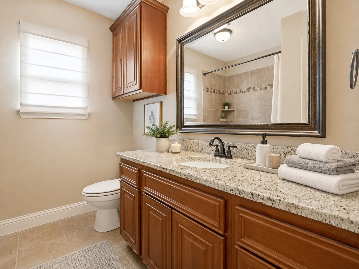 Bathroom featuring a rich wood-finish vanity with a speckled countertop, undermount sink, and dark-tone faucet