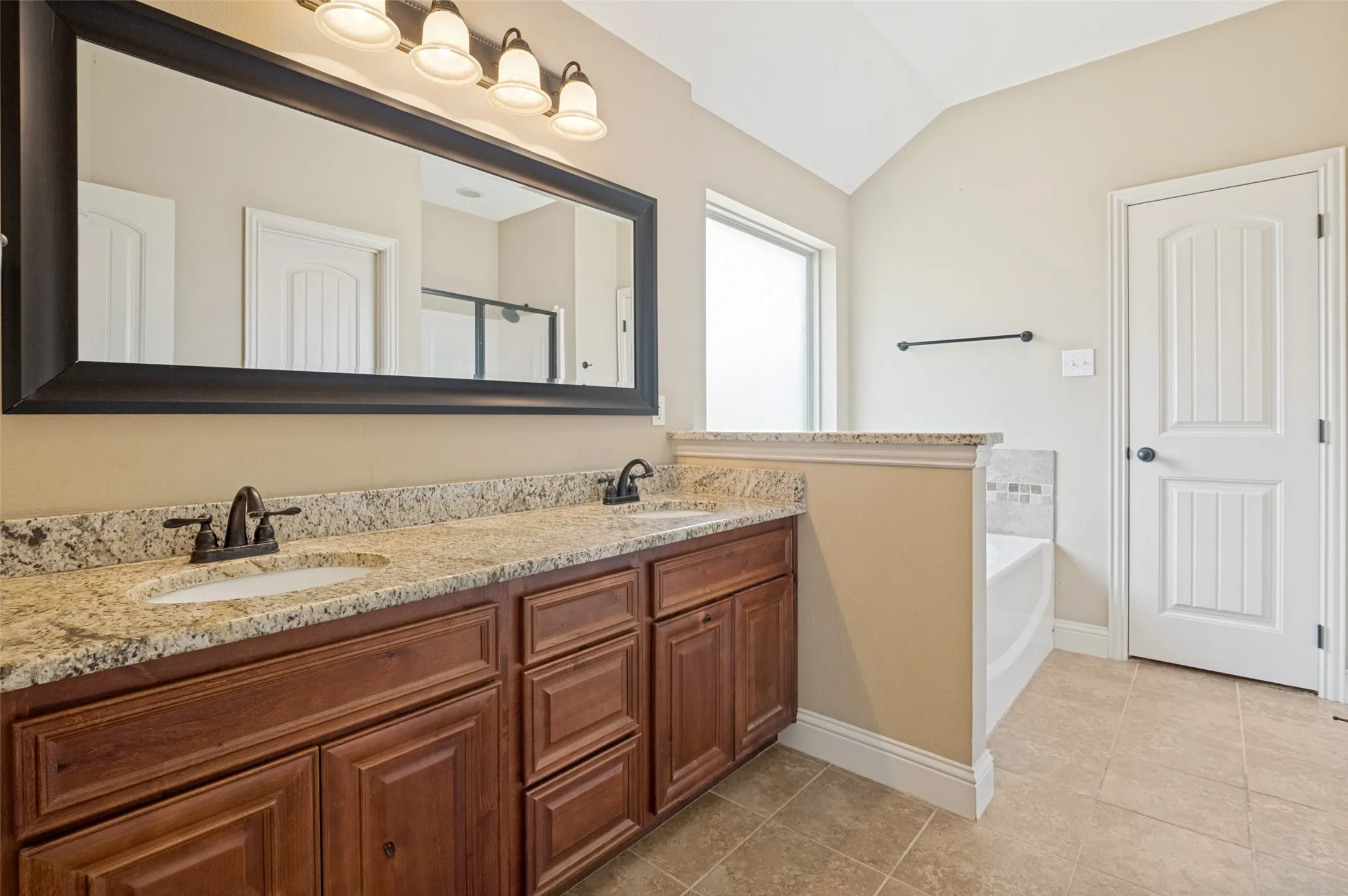 Bathroom featuring a double vanity with stone countertops, integrated oval sinks, and dark bronze fixtures