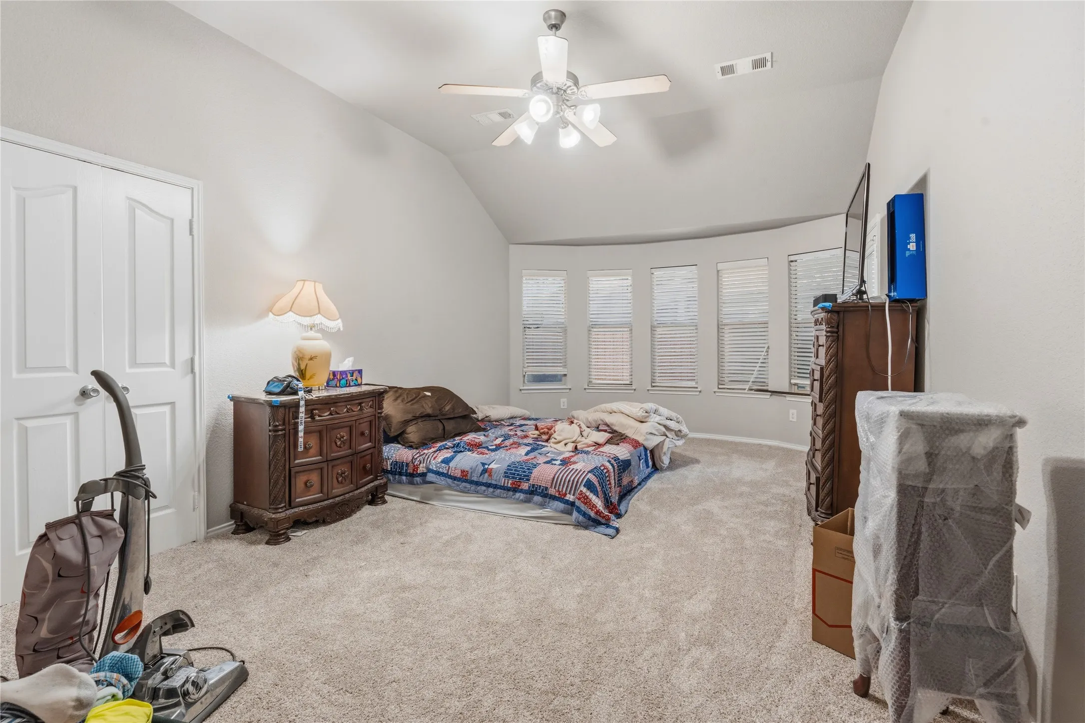 Spacious room featuring vaulted ceilings and light-colored carpeting