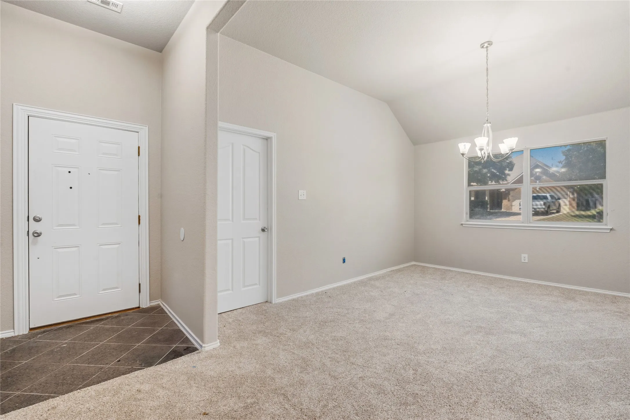 Carpeted room with vaulted ceilings and a multi-light chandelier